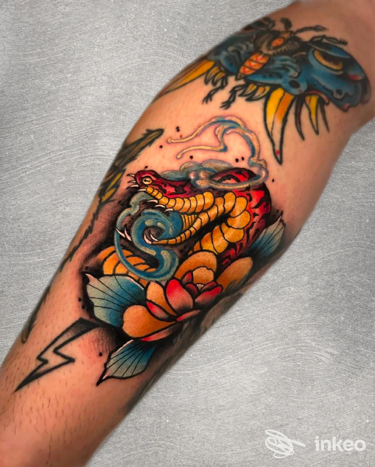 Primo piano di un avambraccio tatuato con serpente colorato e fiori, Black Blood Tattoo & Barber, Casarano.
