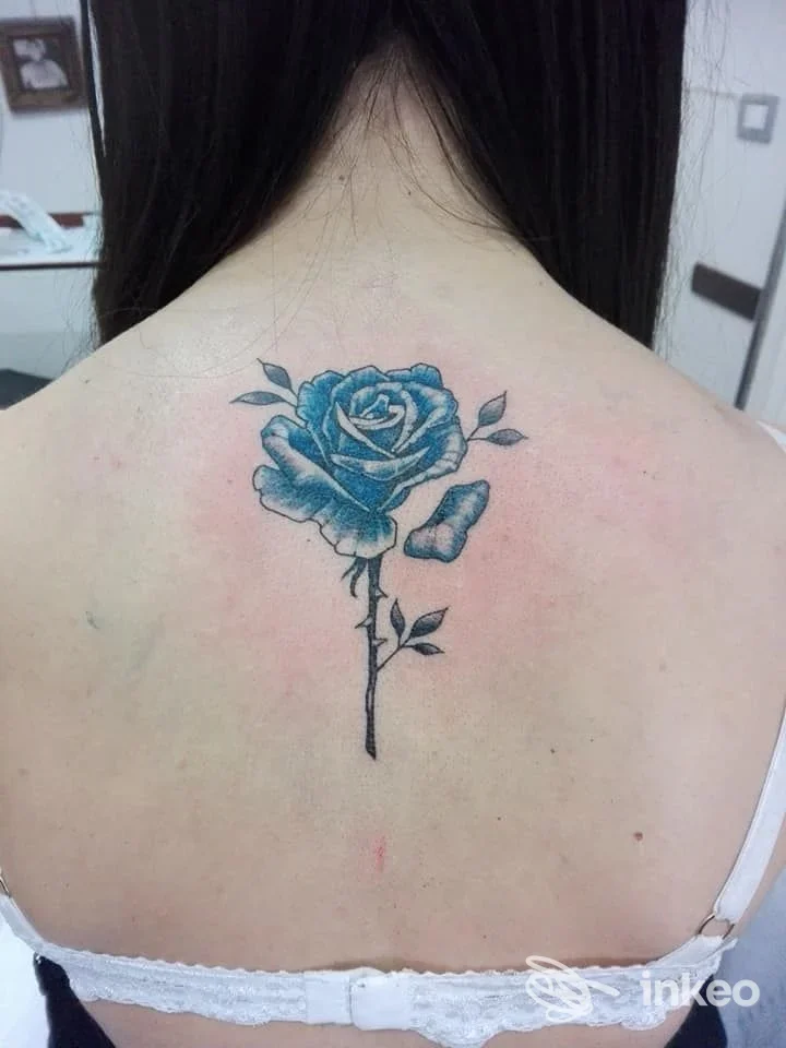 Tatuaggio di una rosa blu sul dorso superiore di una cliente, foto caricate da AtipikoTattoo a Bari.