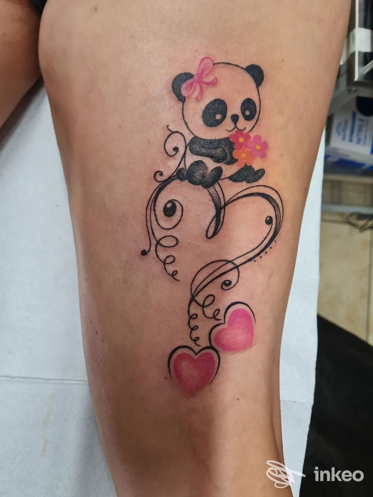 Tatuaggio colorato di un panda con fiore e due cuori rosa sul polpaccio, realizzato da Black Mamba Tattoo, Calimera.