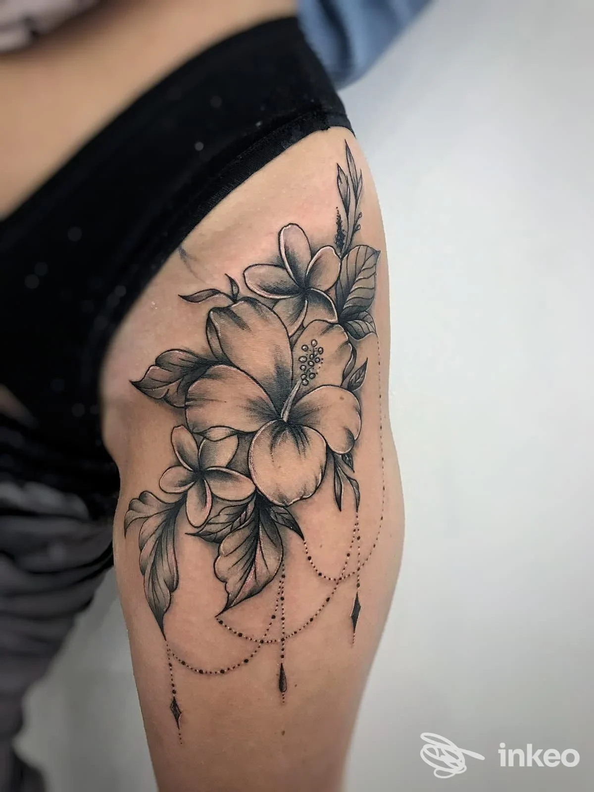 Tatuaggio floreale in bianco e nero sulla parte superiore della coscia, realizzato da Black Mamba Altamura Tattoo ad Altamura.