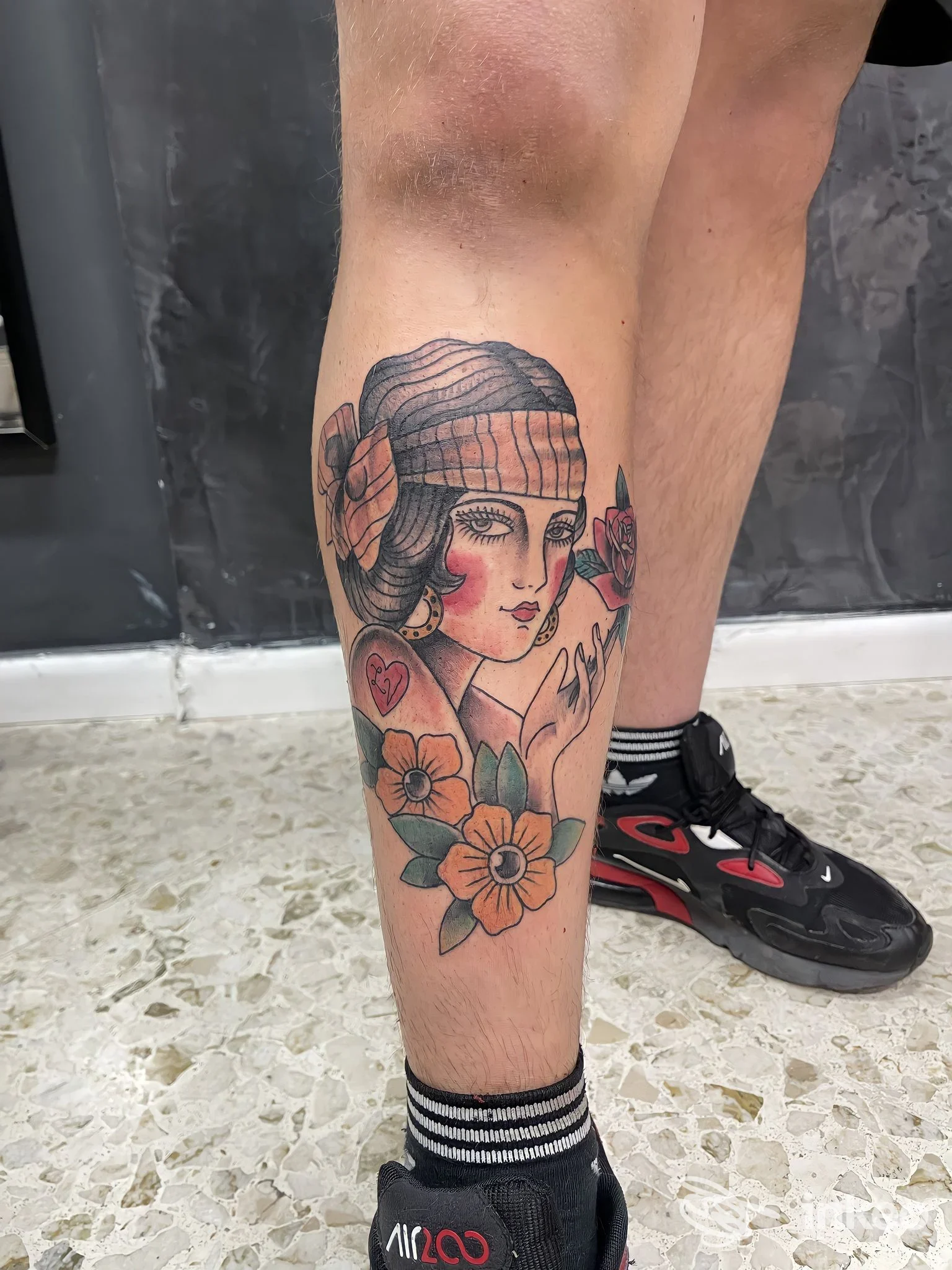 Foto di un tatuaggio ritratto femminile con fiori sul polpaccio, realizzato da Black Mirror Tattoo a Andria.