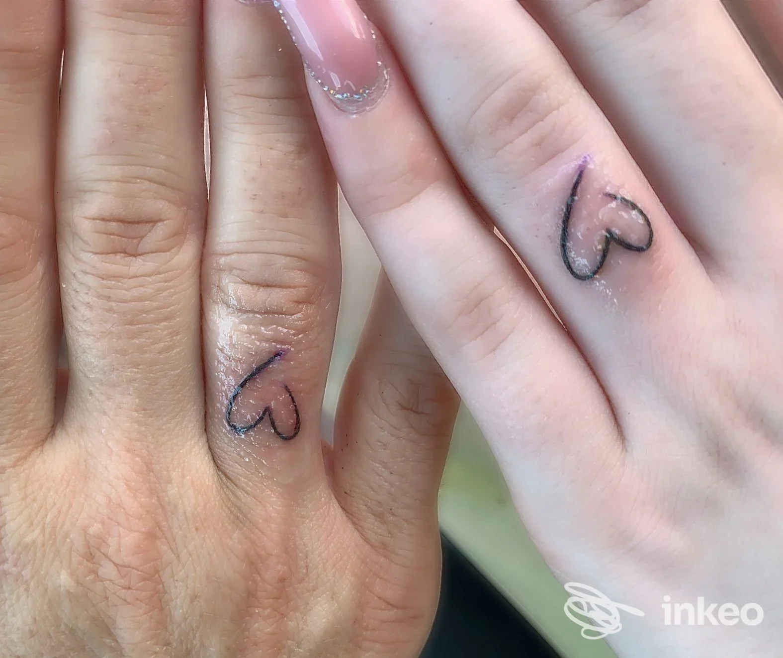 Primo piano di due mani con piccoli cuori tatuati sugli anulari, Blue Mind Tattoo, Presicce-Acquarica.