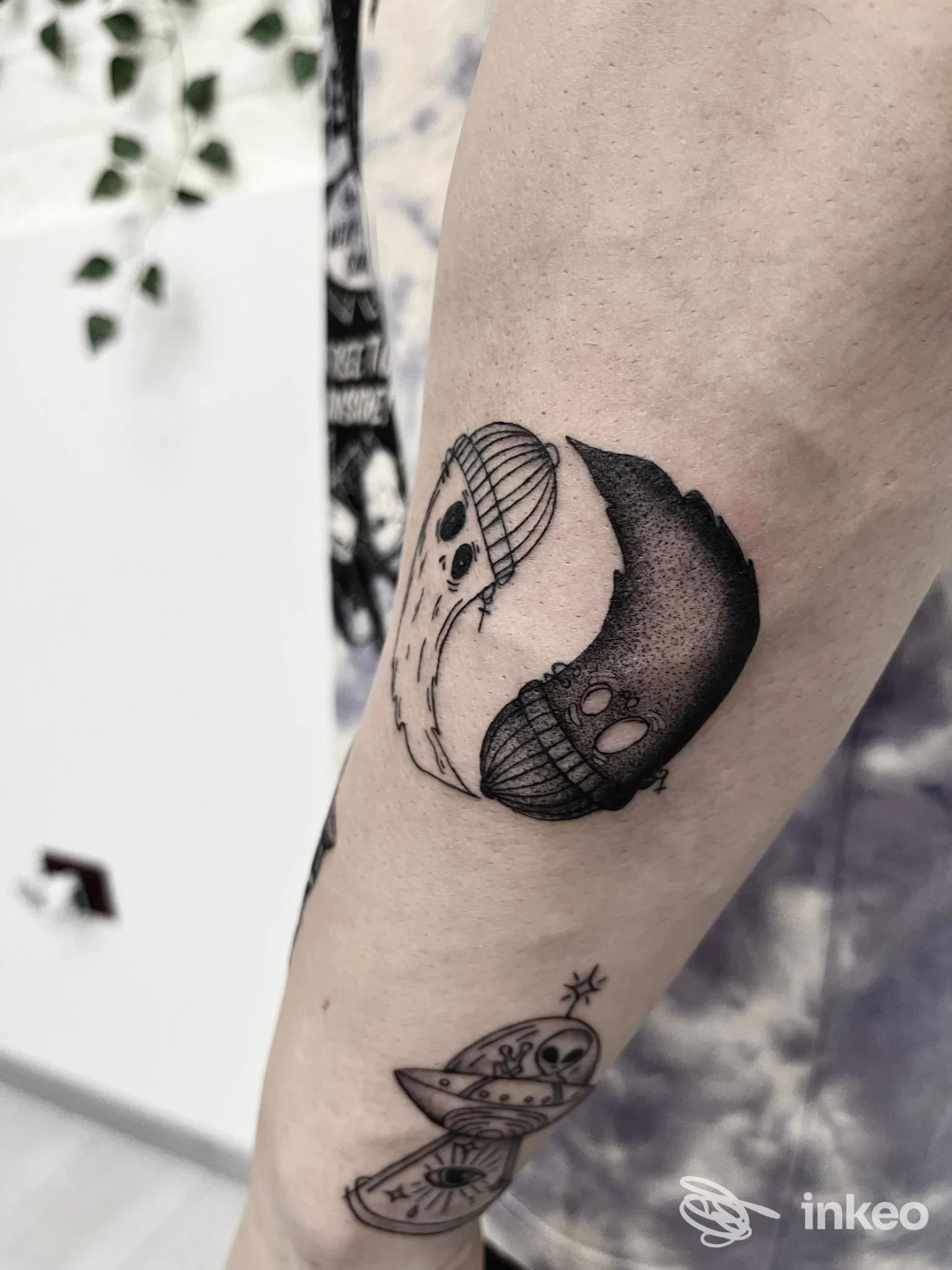 Tatuaggi in bianco e nero su avambraccio: motivo yin-yang scheletrico e piccolo UFO. Black Rose Tattoo, Galatina.