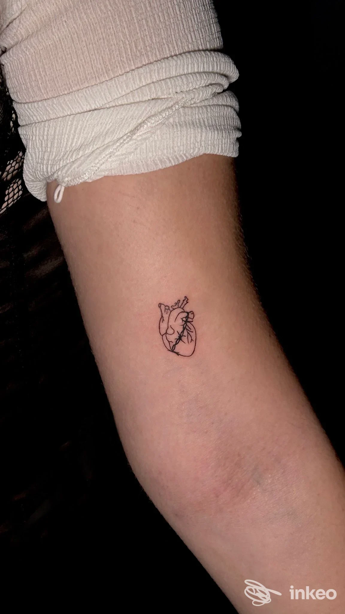 Piccolo tatuaggio a linee nere di un cuore anatomico sull'avambraccio, foto fornita da Celeste Schifano Tattoo Studio a Maglie.