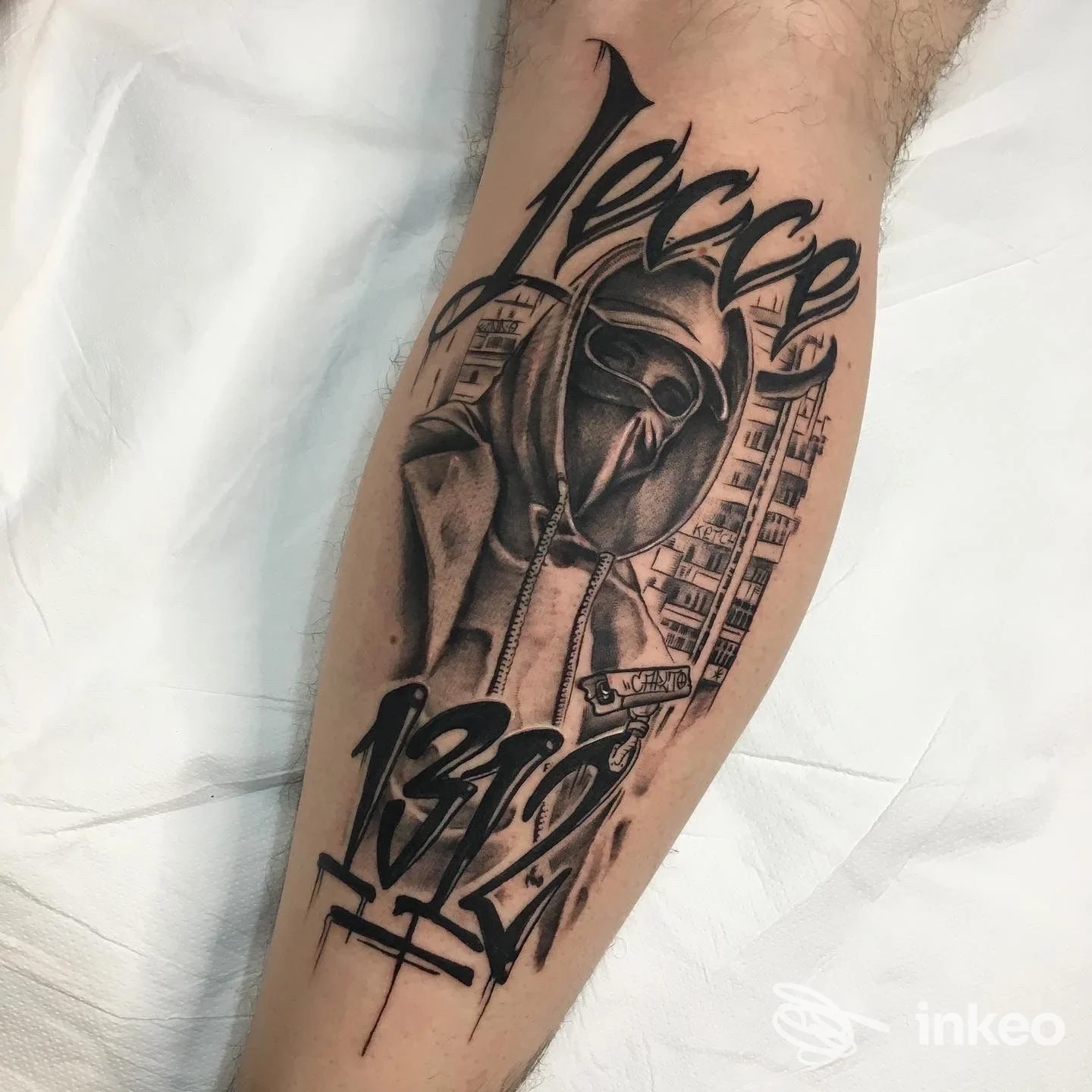 Tatuaggio in bianco e nero su avambraccio raffigurante figura incappucciata e lettering, lavoro eseguito da Carlito Tattoo studio, Poggiardo.