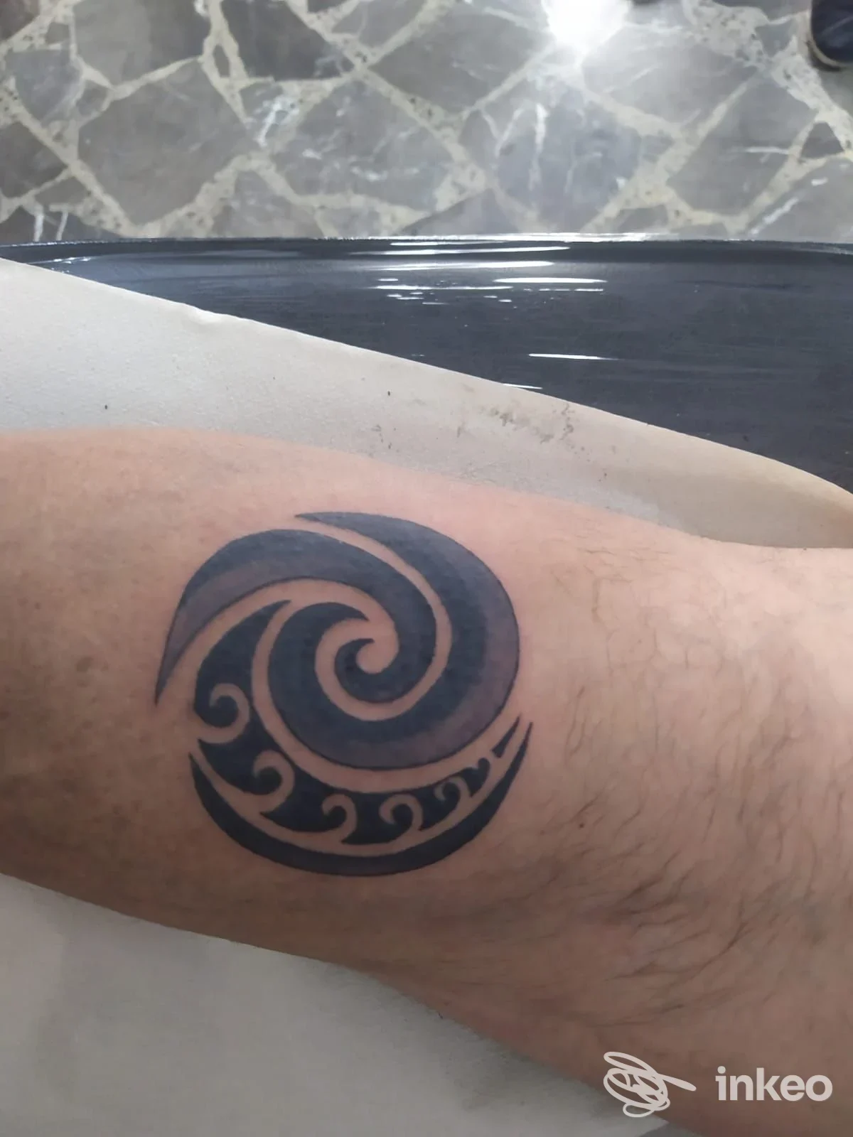 Tatuaggio tribale a spirale in nero sull'avambraccio, fotografato presso Dark light tattoo a San Pancrazio Salentino.
