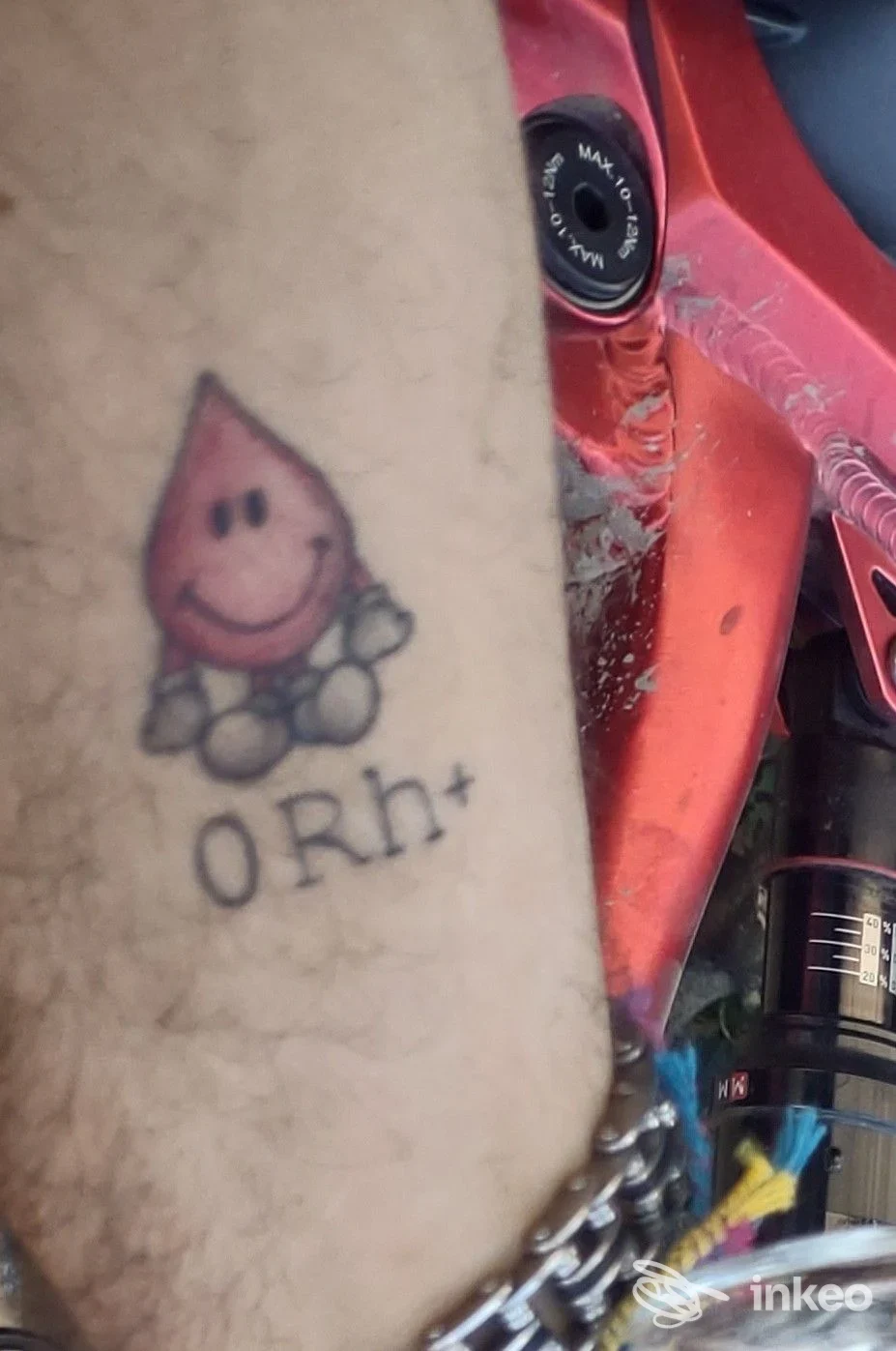 Tatuaggio visibile sull'avambraccio raffigurante una goccia rosa con faccina sorridente.
