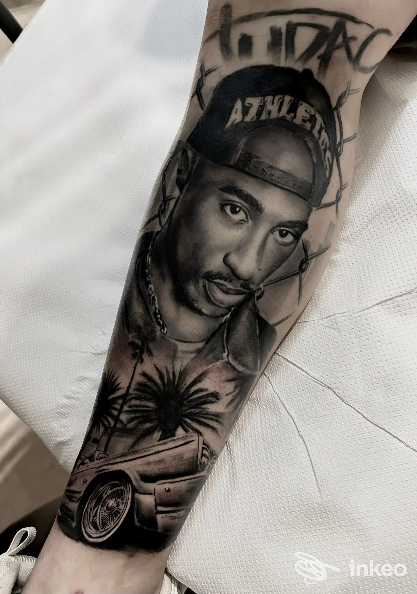 Tatuaggio ritratto realistico su avambraccio, con palme e auto – Doom Tattoo Studio, Cerignola.