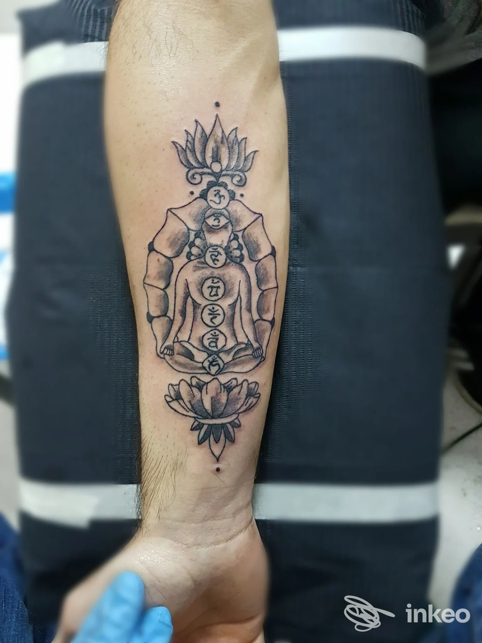 Tatuaggio in bianco e nero sull'avambraccio con figura meditativa, realizzato da Ganeshtattoo&Piercing a Taviano.