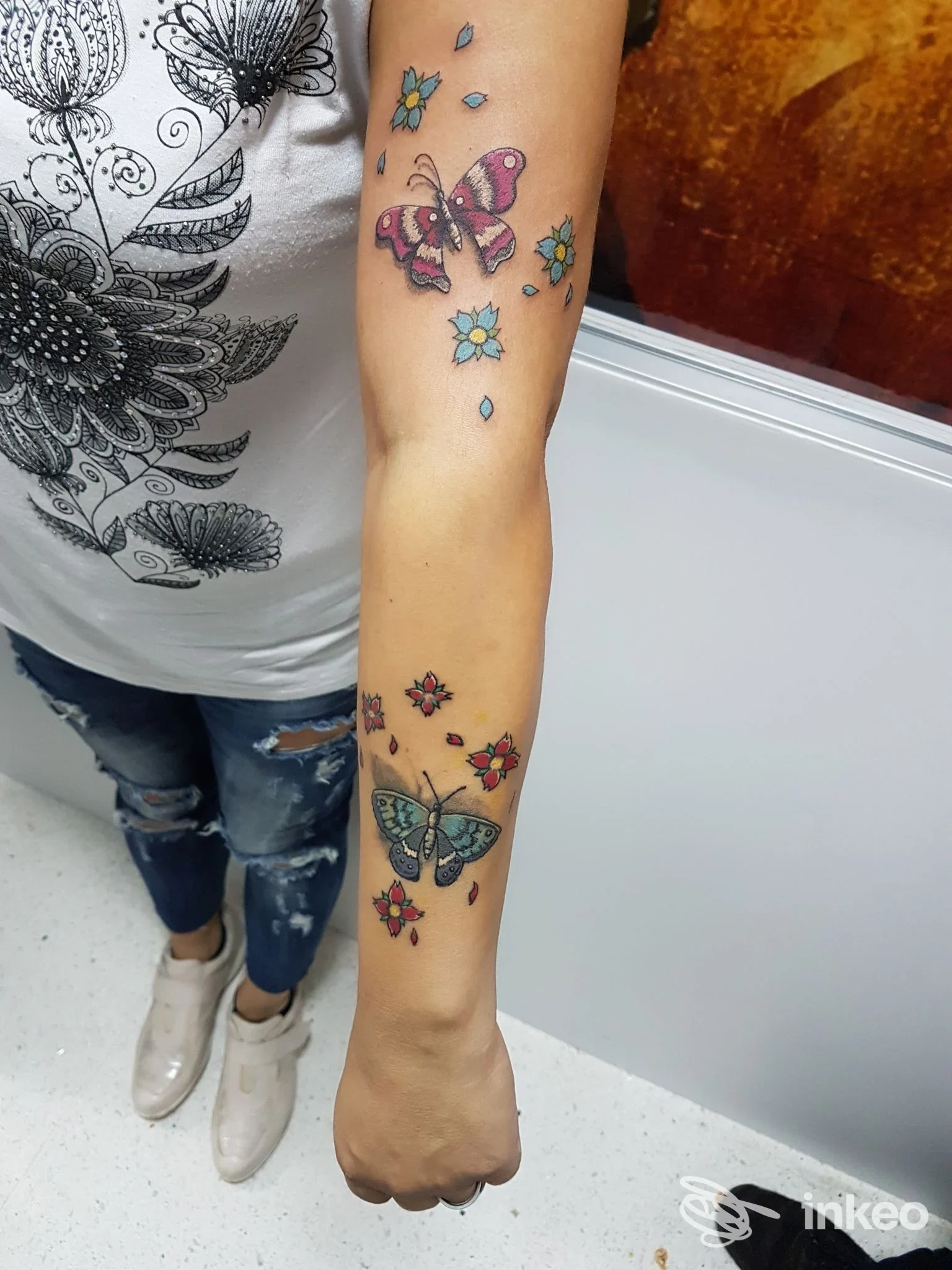 Avambraccio con più tatuaggi colorati a farfalla e fiori, foto fornita da Ganeshtattoo&Piercing, Taviano.