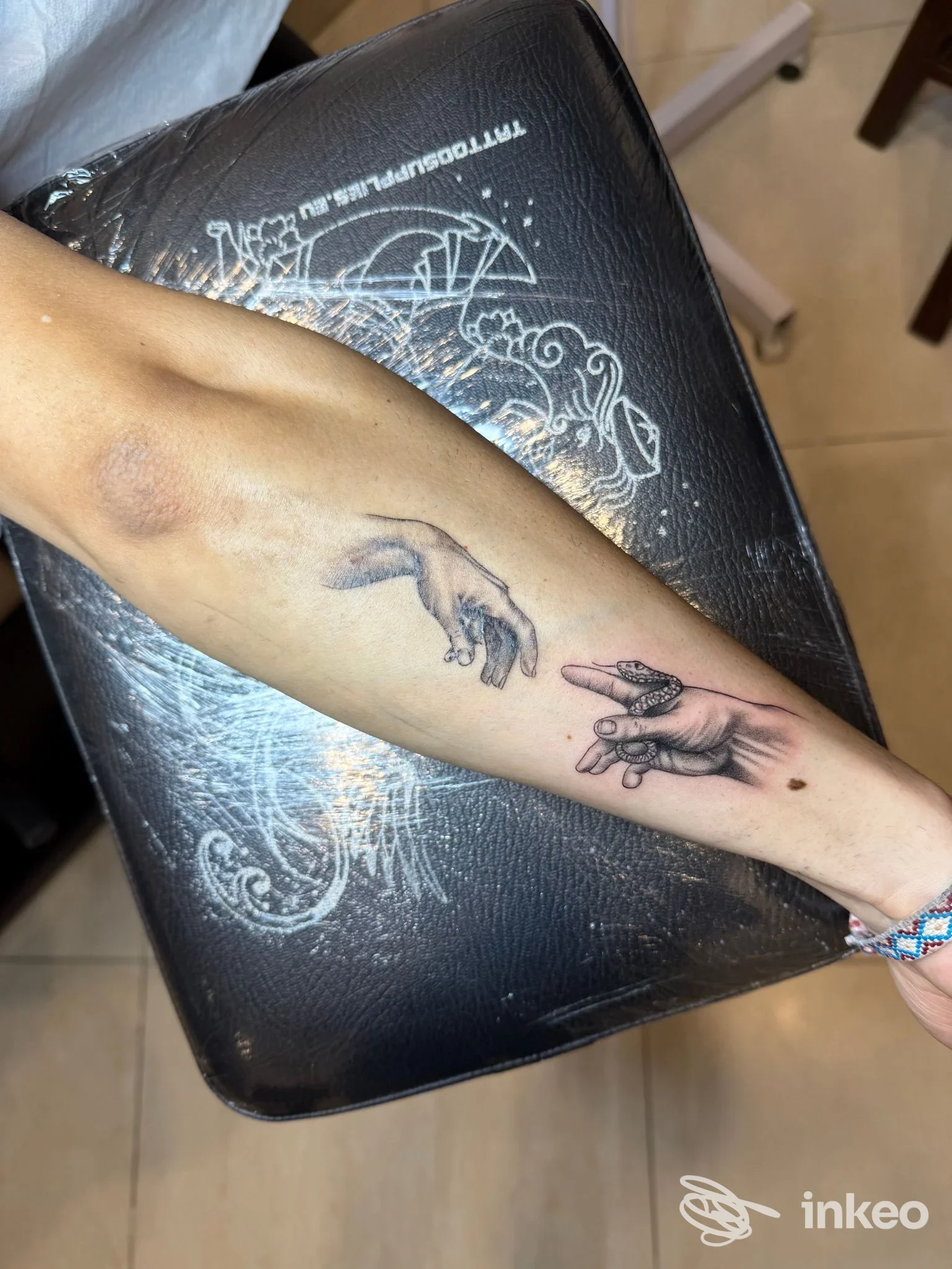 Foto di un avambraccio con tatuaggio a inchiostro nero/grigio raffigurante due mani che si sfiorano, GM TATTOO & PIERCING, Squinzano.