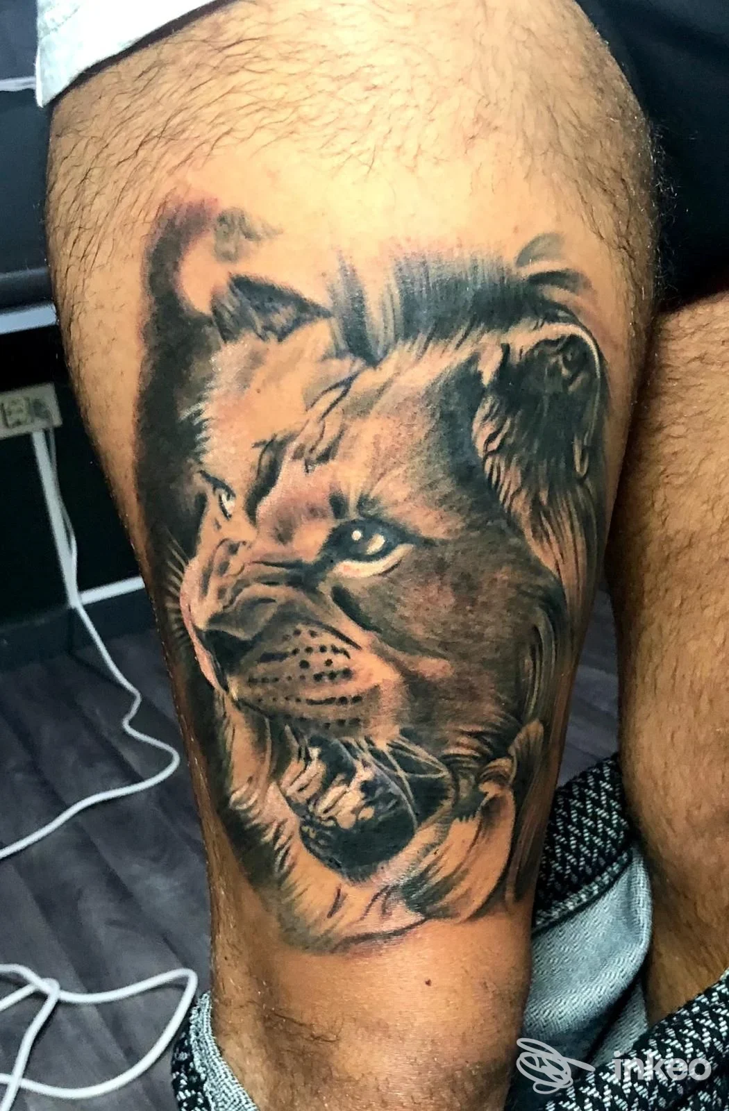 Grande tatuaggio realistico di leone sulla coscia, eseguito da Gigi's Tattoo Shop a Trani, dettaglio in bianco e nero e ombreggiature precise.