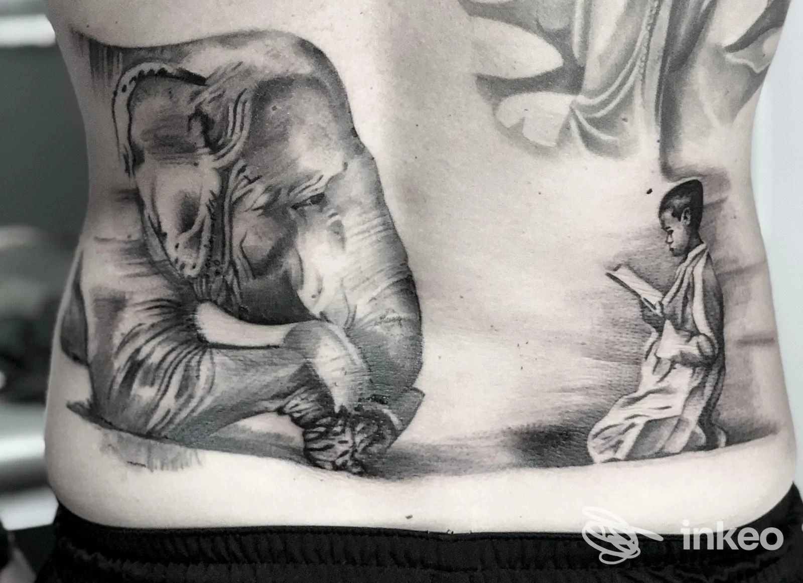 Tatuaggi black & grey sul lombare: elefante realistico e figura che legge, foto fornita da Gigi's Tattoo Shop, Trani.