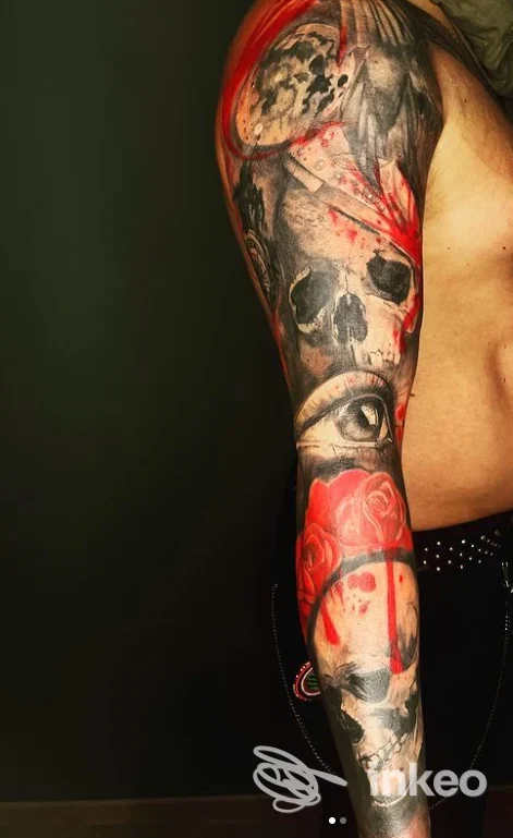 Manica tatuata su braccio destro con teschi, un occhio realistico e rose in nero e rosso — Inklaire Tattoo Shop, San Cesario di Lecce.
