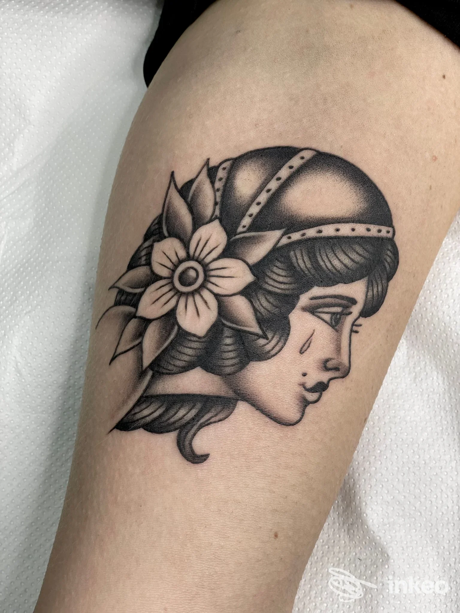 Tatuaggio in nero e grigio di profilo femminile con fiore, realizzato da Inscripta Tattoo a Conversano sulla parte superiore della gamba.