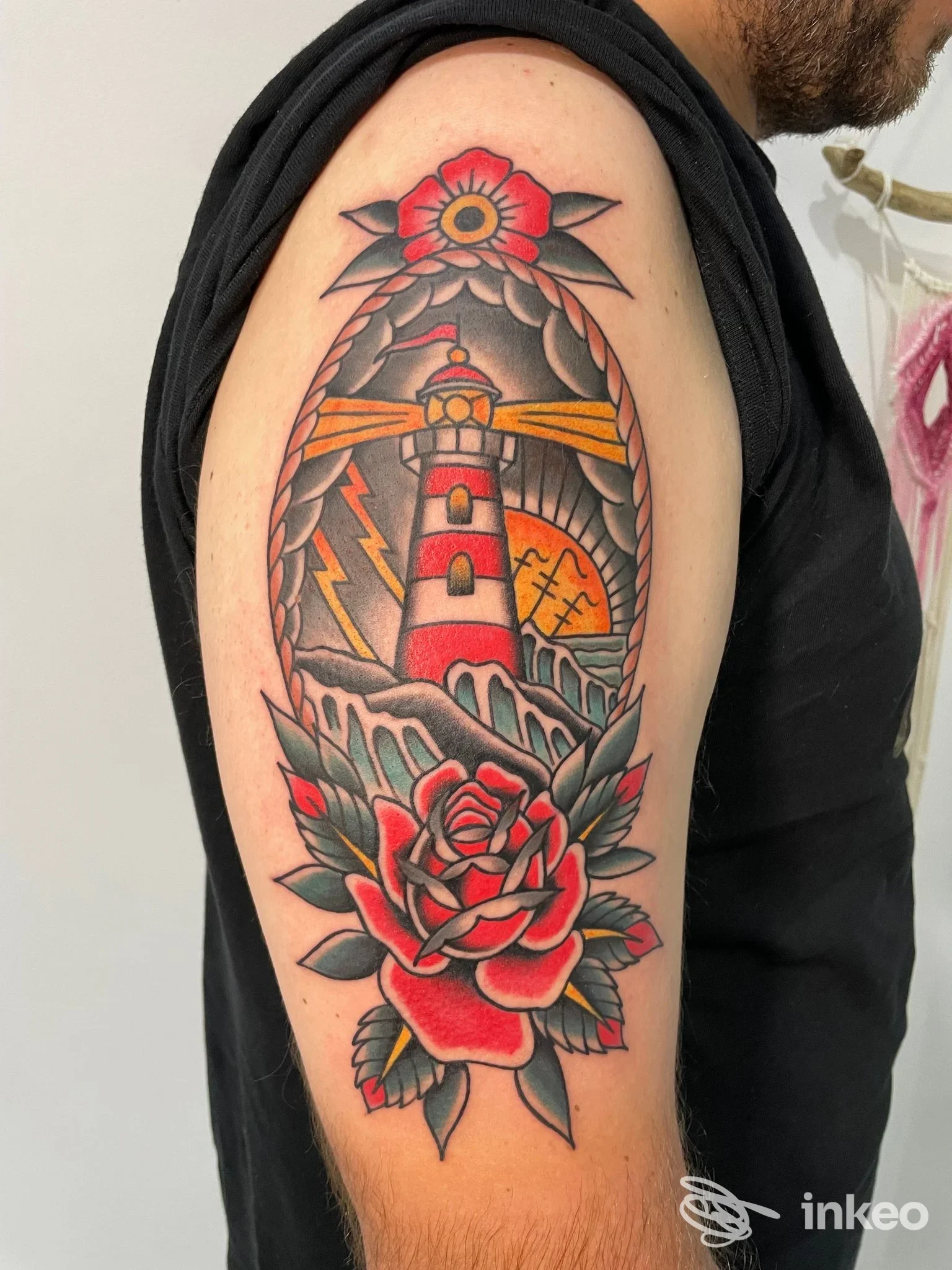Tatuaggio a colori su braccio superiore con faro e rosa, Inscripta Tattoo, Conversano.