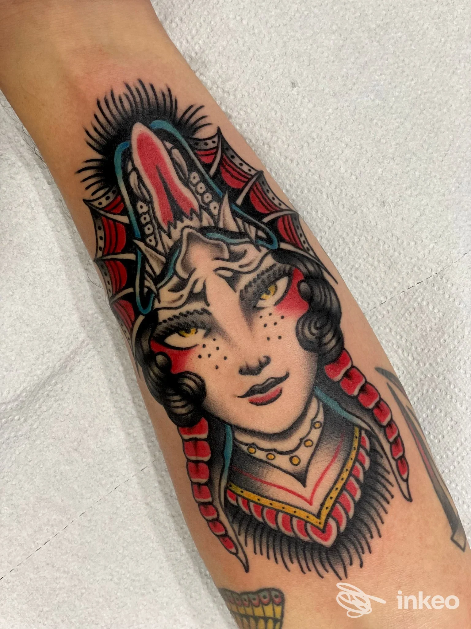 Tatuaggio tradizionale su avambraccio raffigurante volto femminile con dettagli rossi e neri, realizzato da Inscripta Tattoo a Conversano.