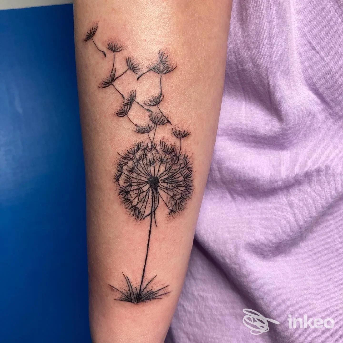 Tatuaggio di soffione stilizzato sull'avambraccio, linee sottili e semi in volo, realizzato da IDA TATTOO STUDIO a Foggia.