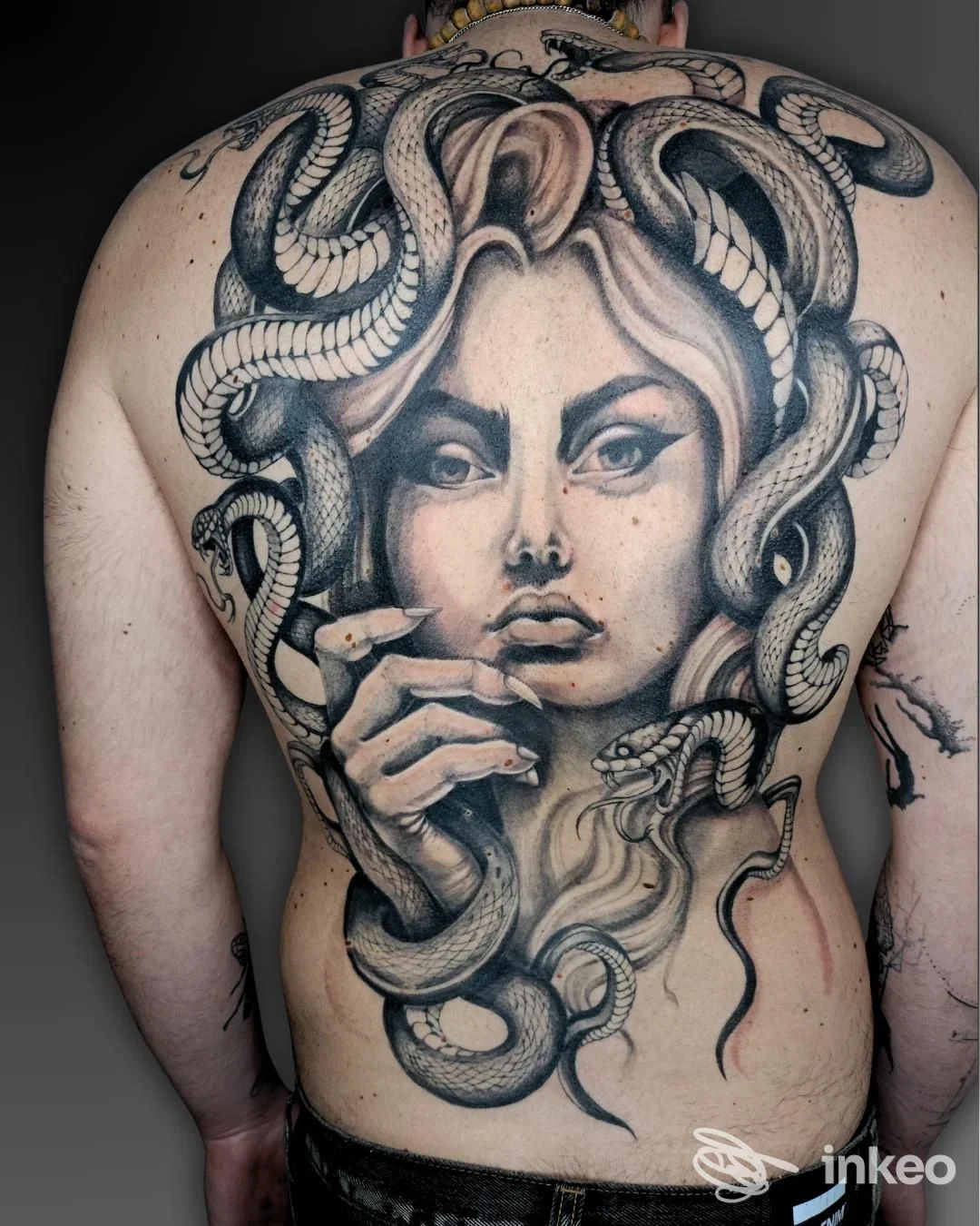 Grande tatuaggio black-and-grey su tutta la schiena raffigurante un volto femminile e serpenti — Inkonica Tattoo, Noci.