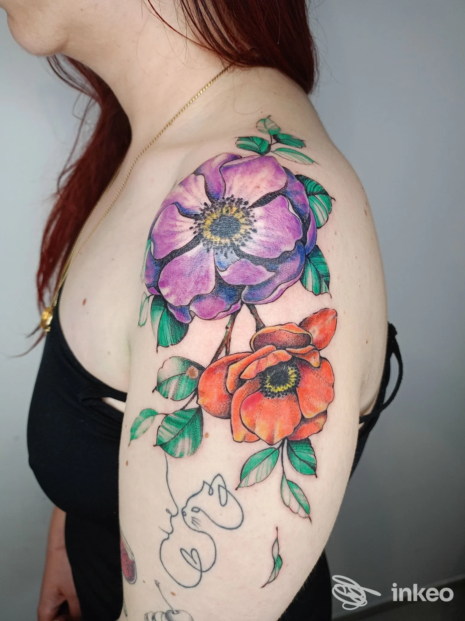 Grande tatuaggio floreale colorato sulla spalla e braccio, realizzato da Inkonica Tattoo a Noci.