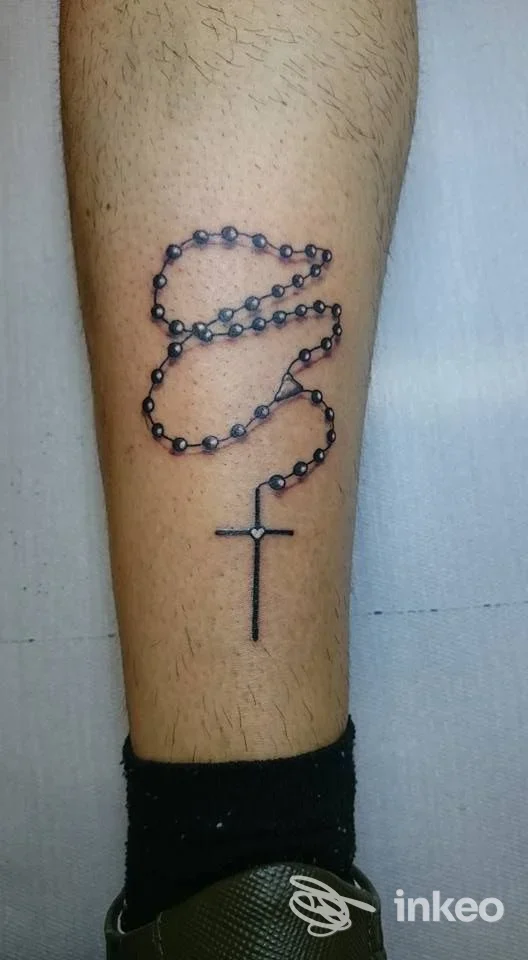 Tatuaggio di un rosario con perline e croce sul polpaccio di un cliente, realizzato da Jack Tattoo Capurso a Capurso.