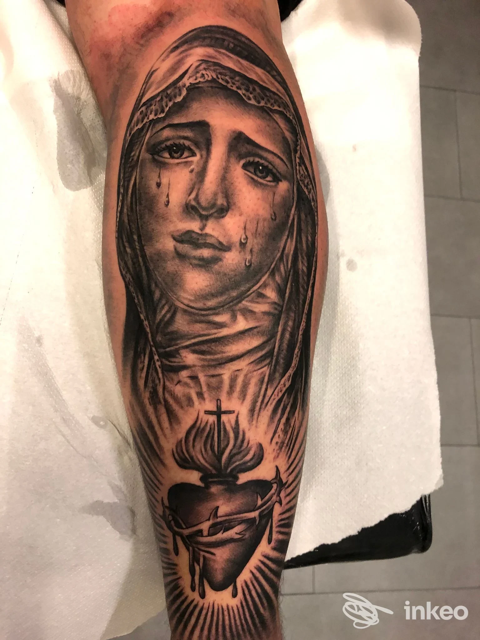 Tatuaggio su avambraccio raffigurante una donna piangente in stile realistico, con cuore in basso, eseguito in bianco e nero.