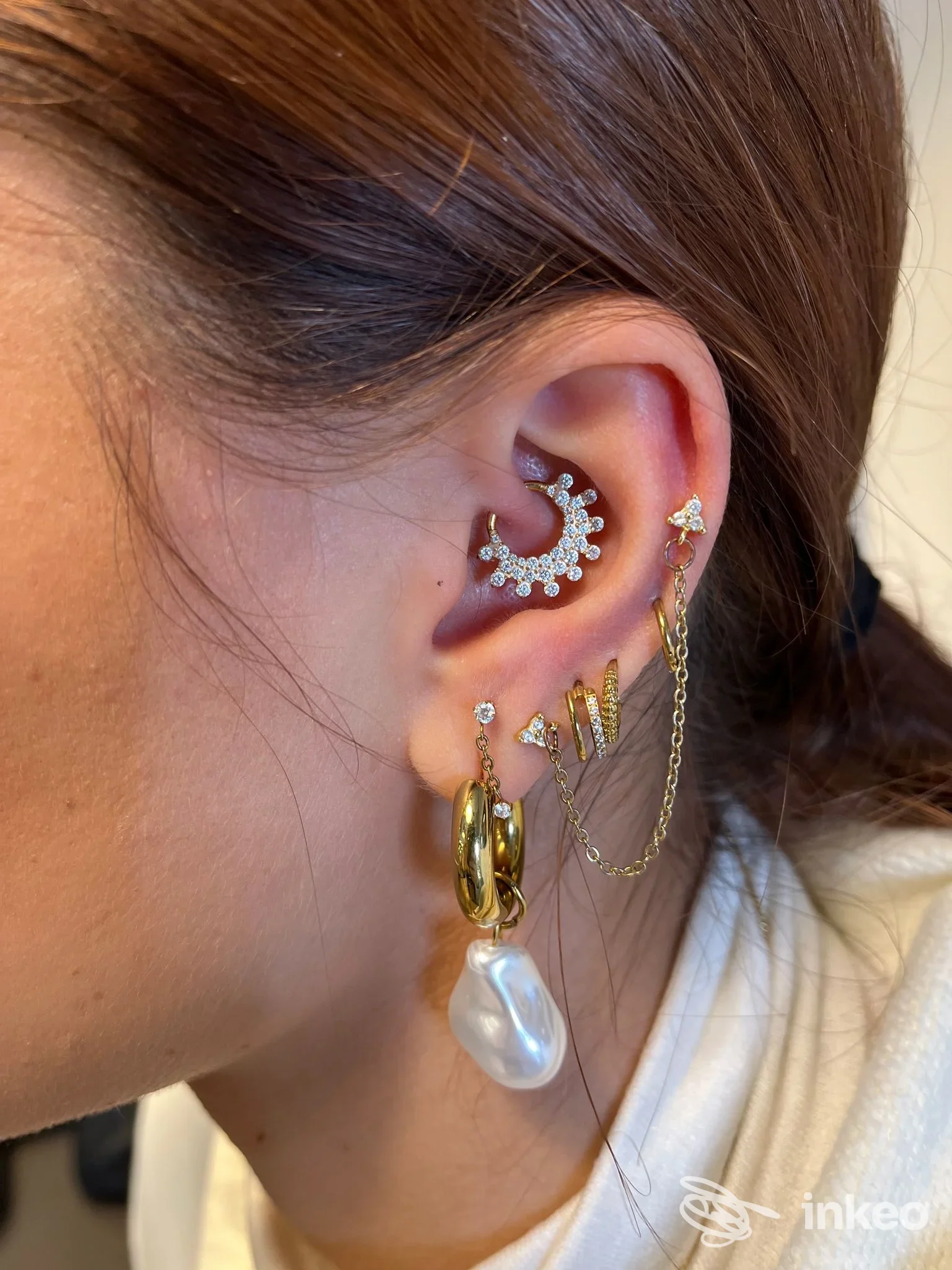 Orecchio con più piercing dorati, pietre bianche e perla pendente, lavoro piercing di LA LORE PIERCING, Bari.