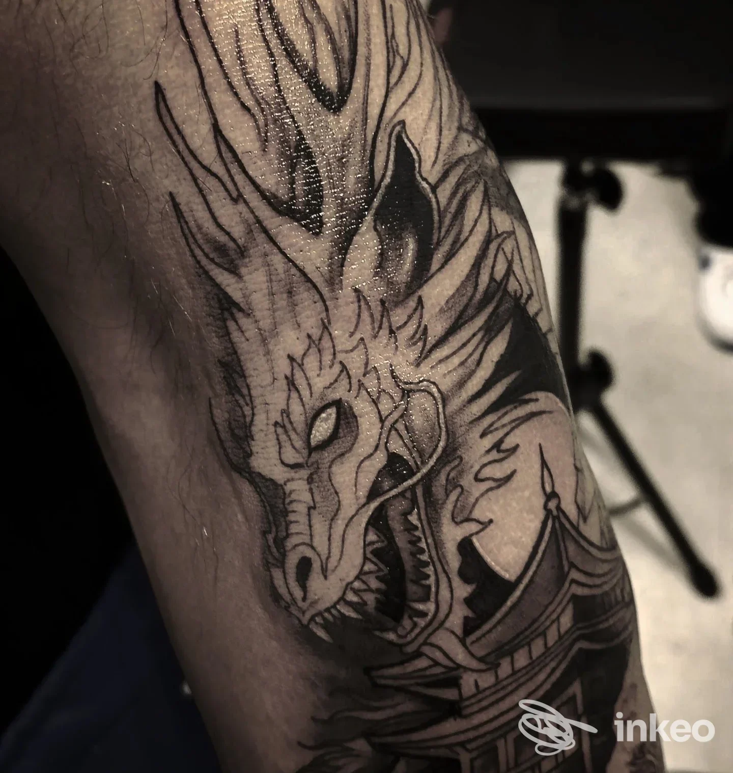 Tatuaggio dettagliato in nero raffigurante una testa di drago e una pagoda sull'avambraccio, fotografato nello studio Luke Rux tattoo studio a Rignano Garganico.
