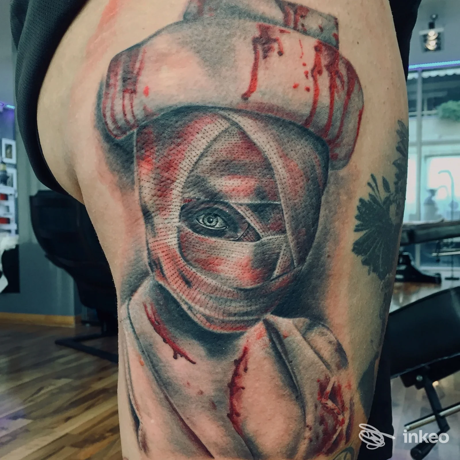 Tatuaggio realistico con figura bendata e dettagli rossi, eseguito da Magic Tattoo di Giorgio Guido a Mesagne sulla coscia del cliente.