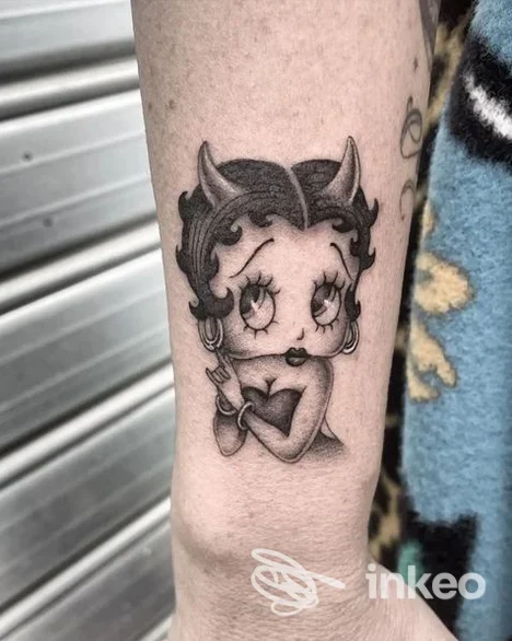 Tatuaggio in bianco e nero raffigurante un personaggio cartoon con corna sull'avambraccio, scatto dello studio Más Profundo Tattoo Shop, Taranto.