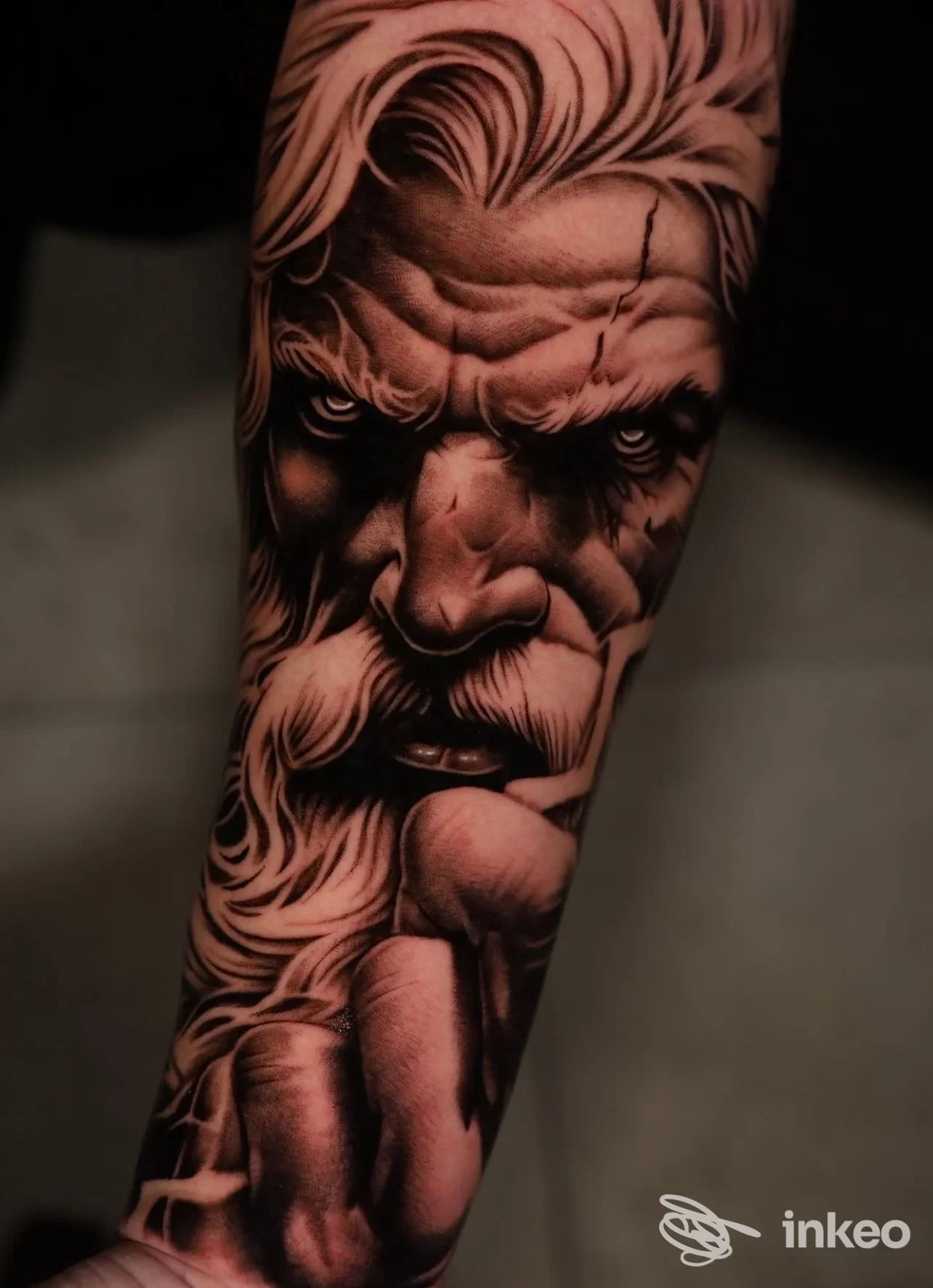 Primo piano di un tatuaggio realistico di un volto maschile su avambraccio umano, molto dettagliato e con forti ombreggiature. MOB Tattoo Shop, Sava.