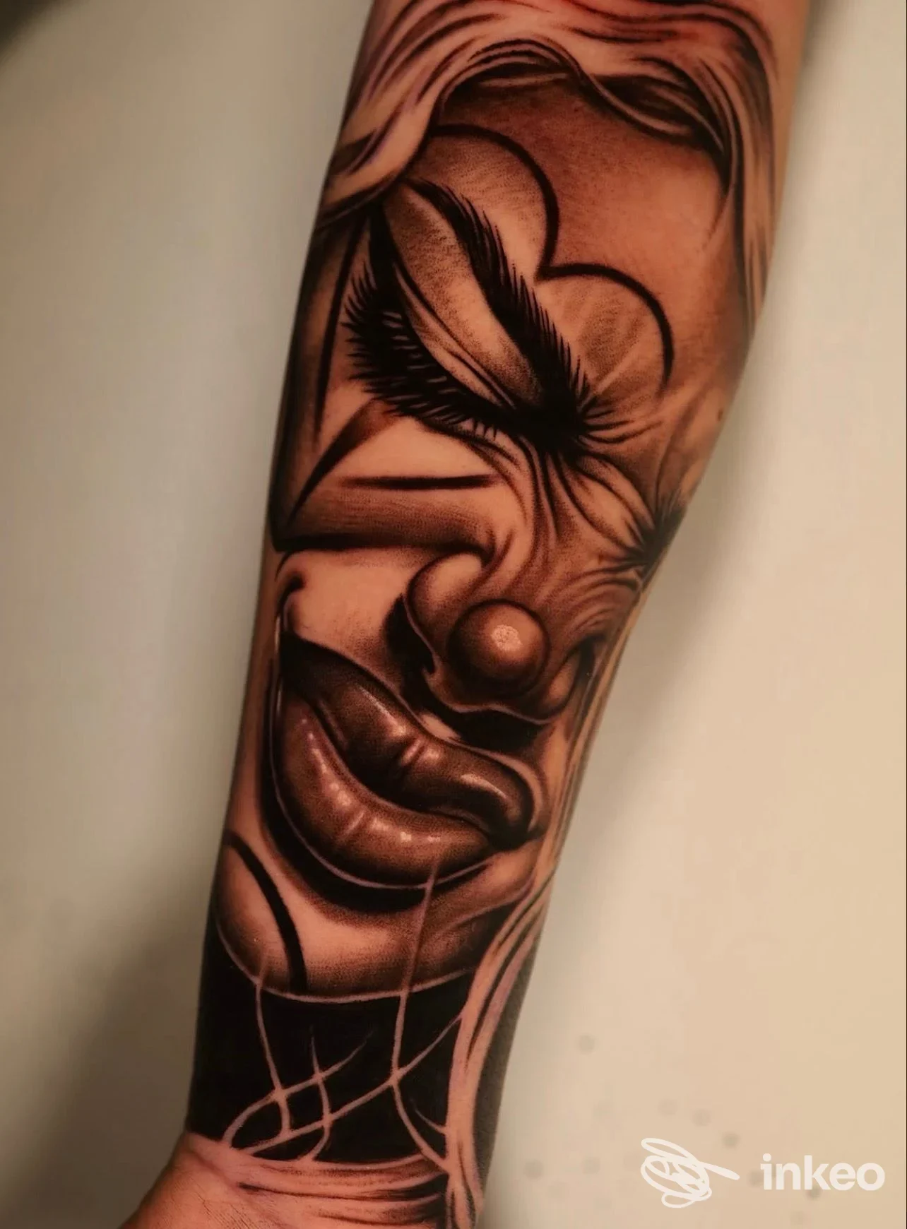 Tatuaggio black-and-grey di un volto/clown su avambraccio, dettagli realistici, MOB Tattoo Shop, Sava.