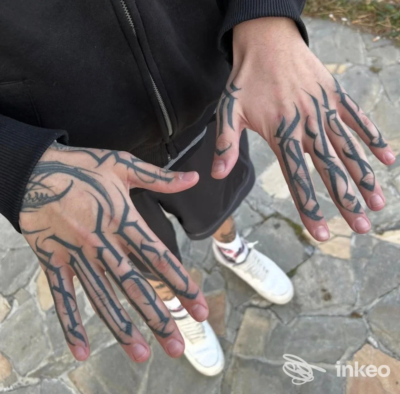 Dettaglio delle mani tatuate eseguite da MOB Tattoo Shop a Sava, tatuaggi neri su dorso e dita.