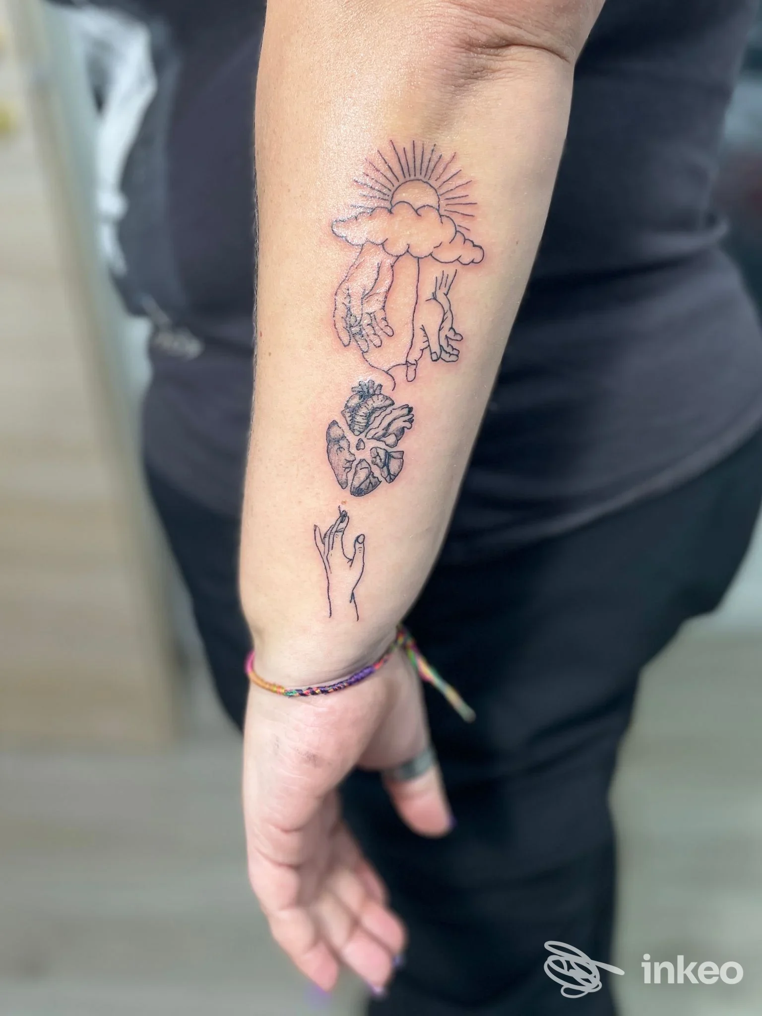 Tatuaggi linework neri su avambraccio sinistro: sole con mani, cuore anatomico e mano stilizzata. Macedone Shop Tattoo & Piercing, Bari.