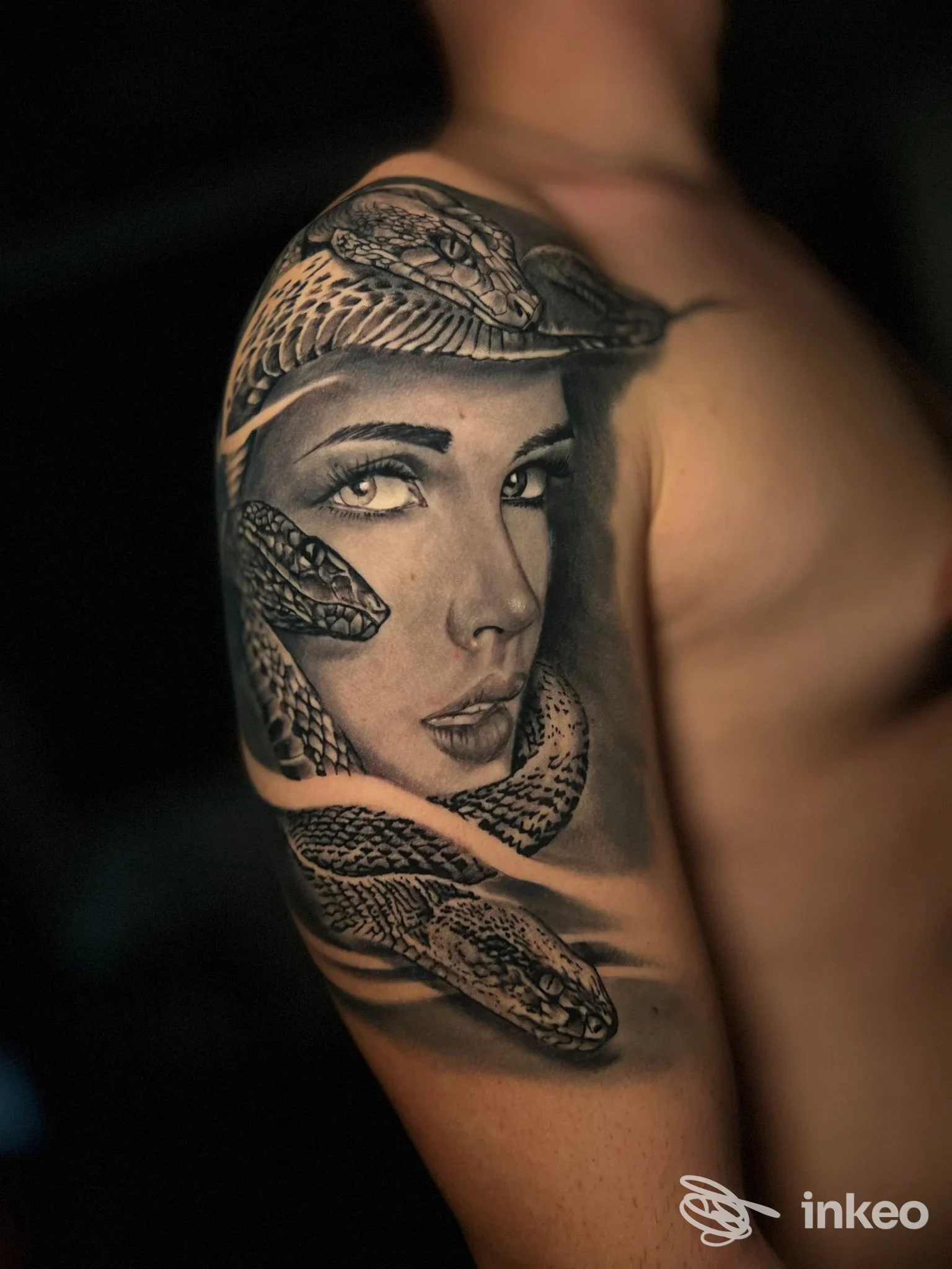 Tatuaggio realistico su braccio e spalla con volto femminile e serpenti in bianco e nero, Michael Night Tattoo & Vincent piercing, Taranto.