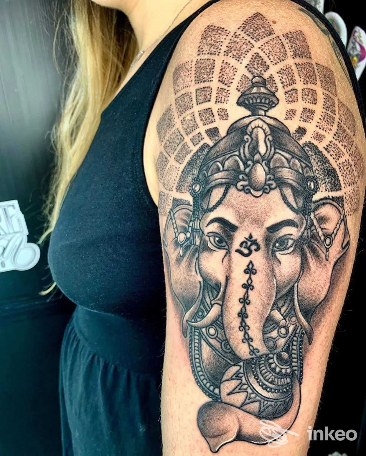 Tattoo sul braccio sinistro raffigurante Ganesh con dettagli ornamentali, sulla pelle reale di una persona, senza volto intero visibile.
