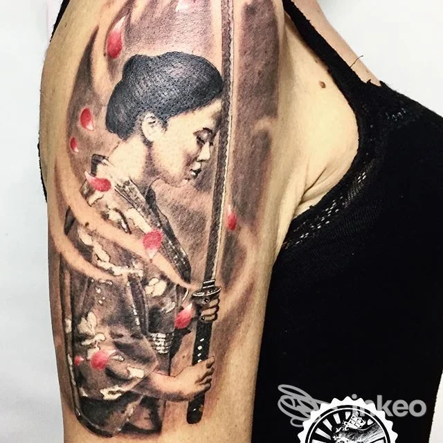 Tatuaggio realistico di figura femminile con spada e petali rossi sul braccio superiore. Nice Tattoo, Taranto.