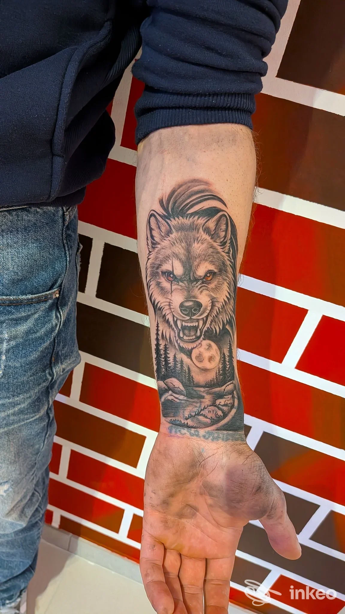 Avambraccio tatuato con testa di lupo realistico e paesaggio; foto fornita da Personalink Tattoo, Cisternino.