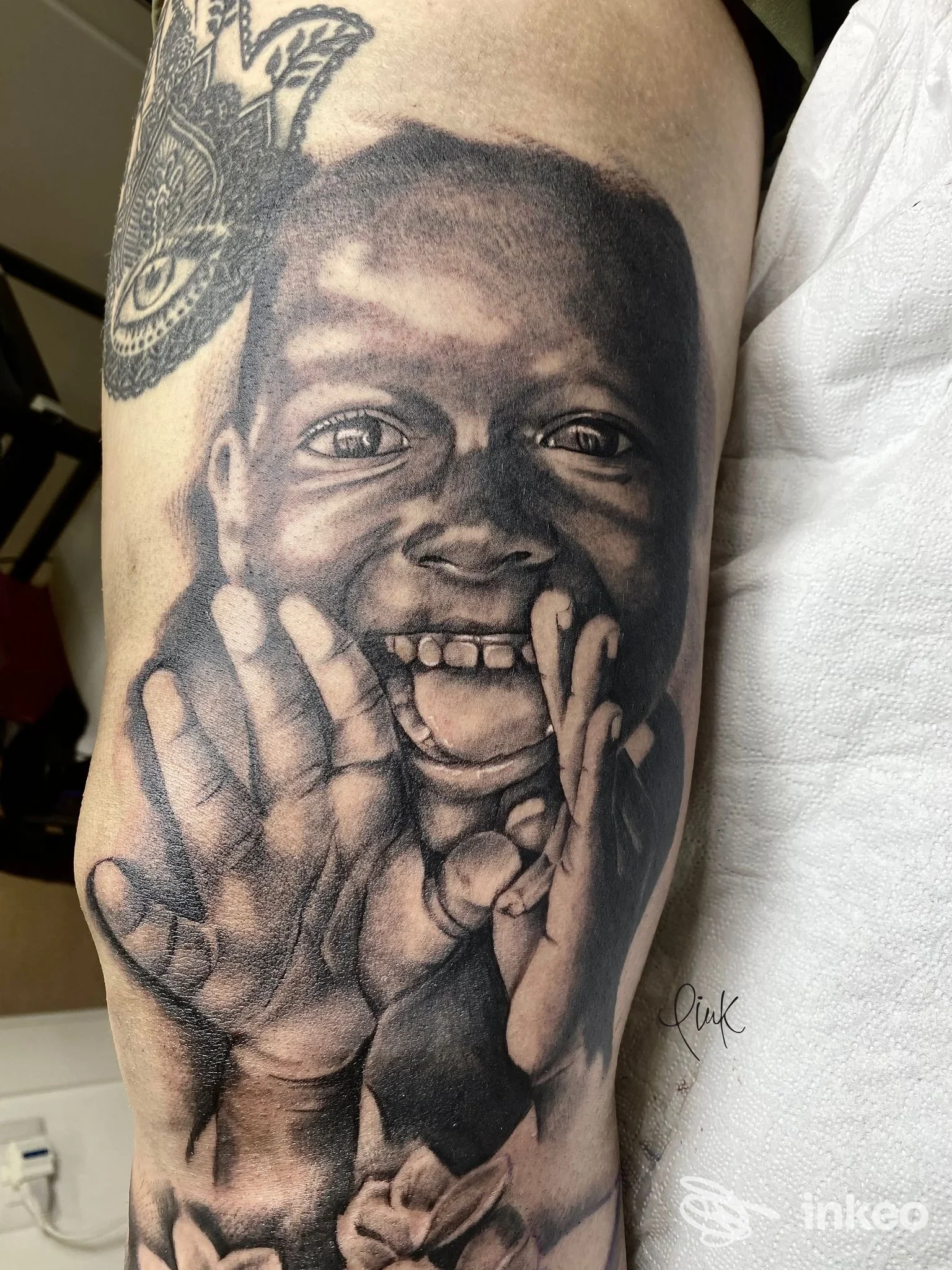 Tatuaggio realistico in bianco e nero di un bambino sorridente sull'avambraccio, eseguito da Pink tattoo&piercing a Castellana Grotte.