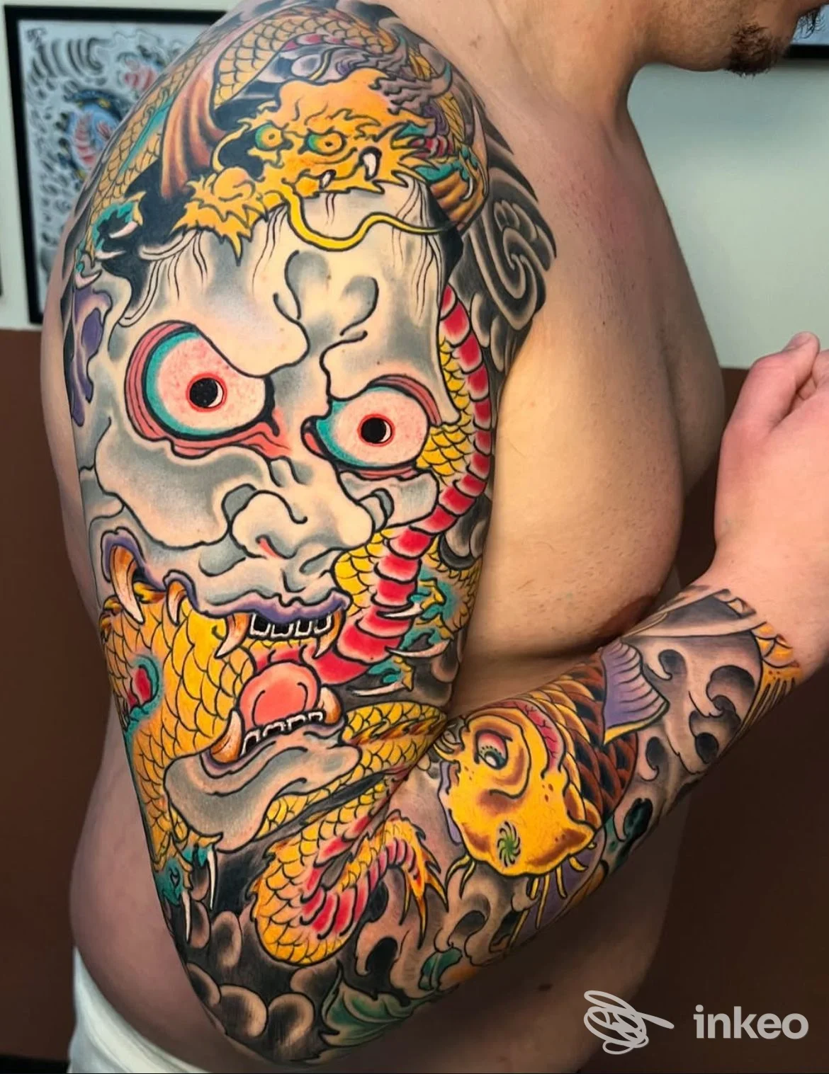 Manica tatuata su spalla e braccio con dragone e maschera colorata, foto fornita da Beyond the skin tattoo studio, Foggia.