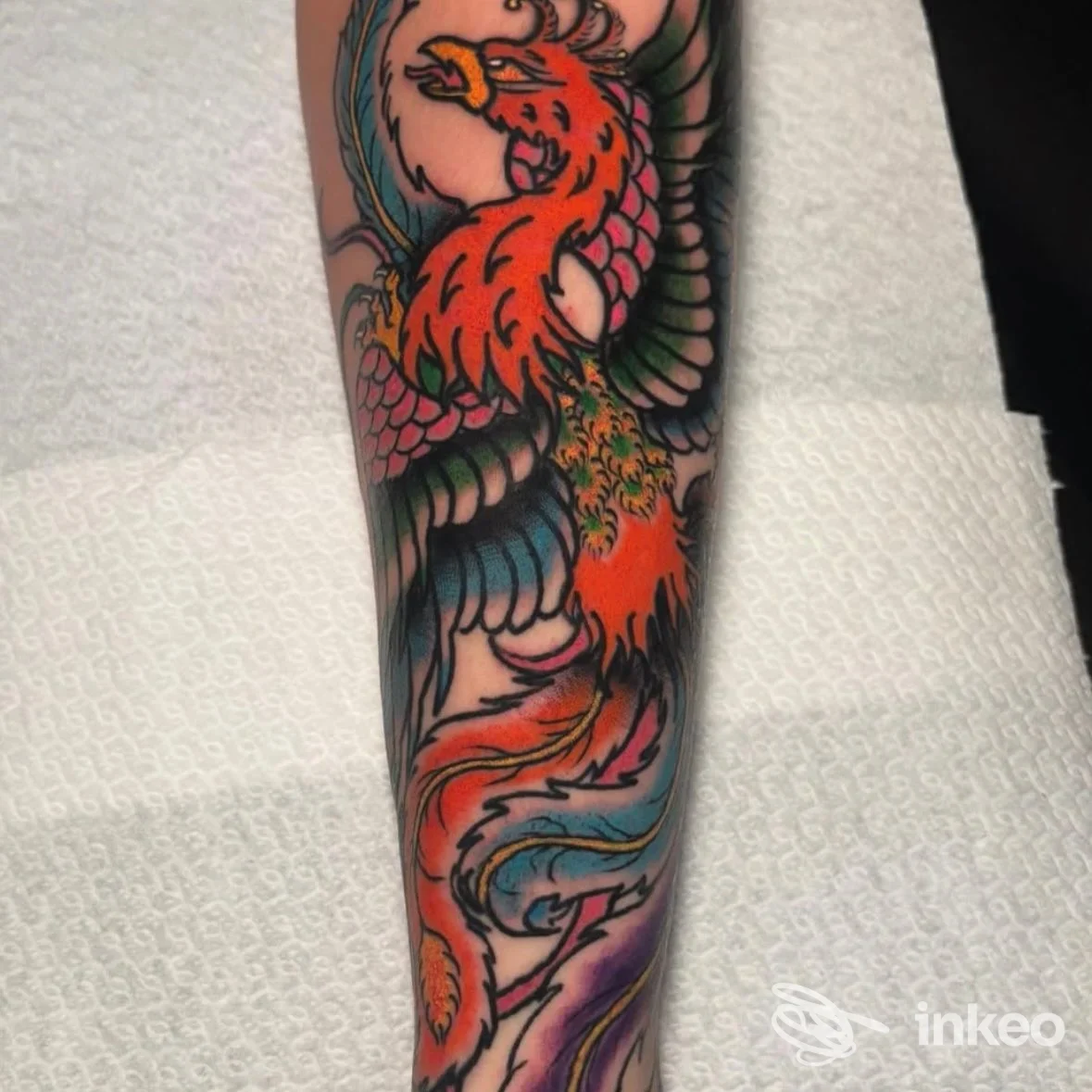 Tatuaggio colorato a tema fenice sull'avambraccio, fotografato per Beyond the Skin Tattoo Studio, Foggia.