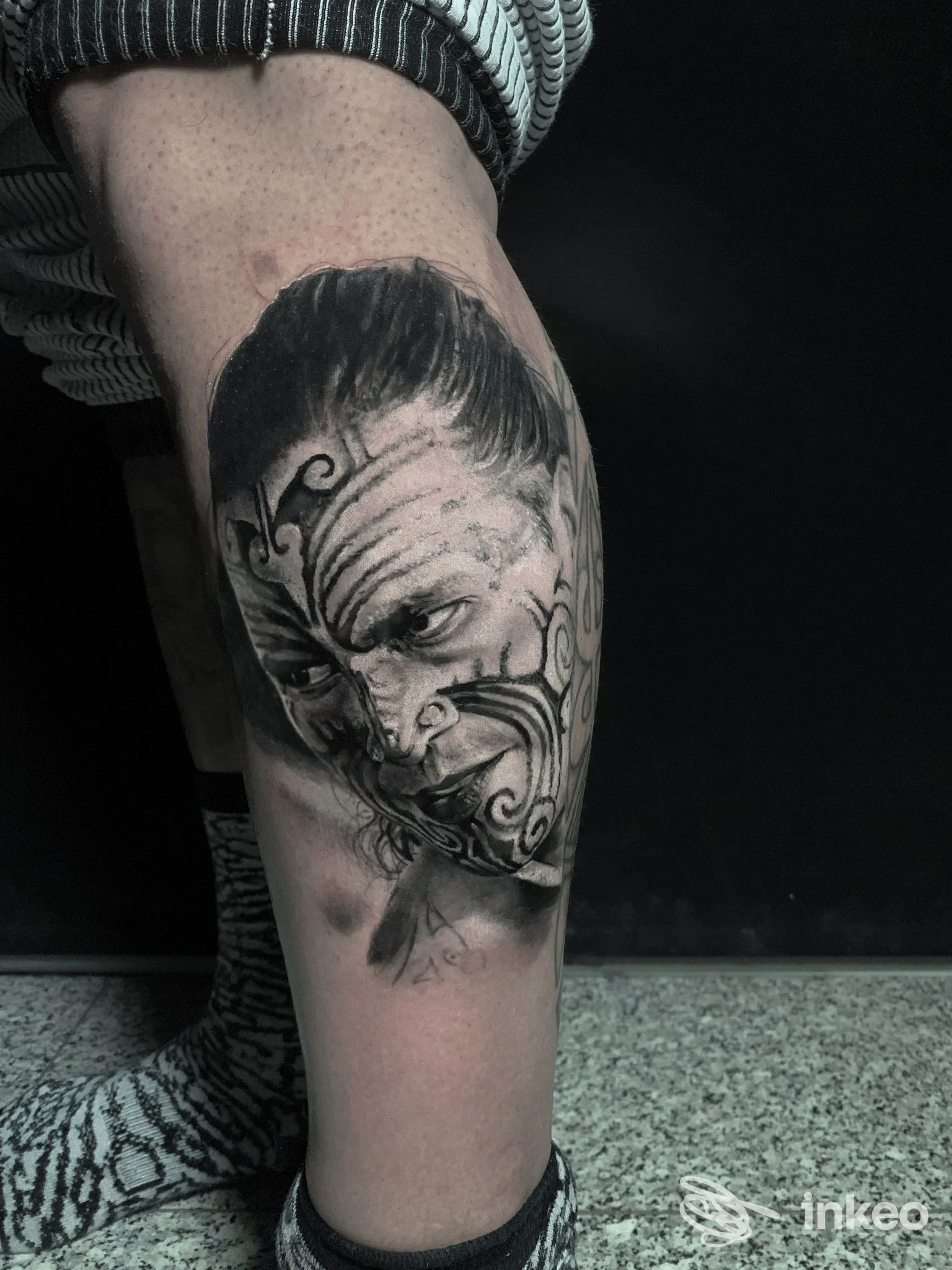 Tatuaggio realistico in bianco e nero raffigurante un volto ornamentale sul polpaccio di un cliente, Daniele Stella Tattoo Shop, Bari.