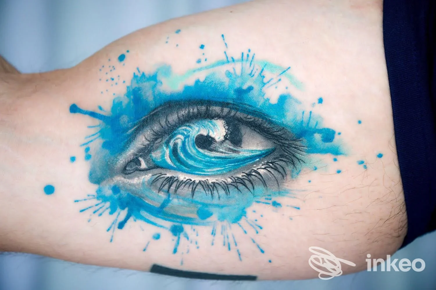 Tatuaggio a colori sull'interno del braccio raffigurante un occhio con onde e schizzi blu, opera mostrata da Debrart Tattoos, Bari.