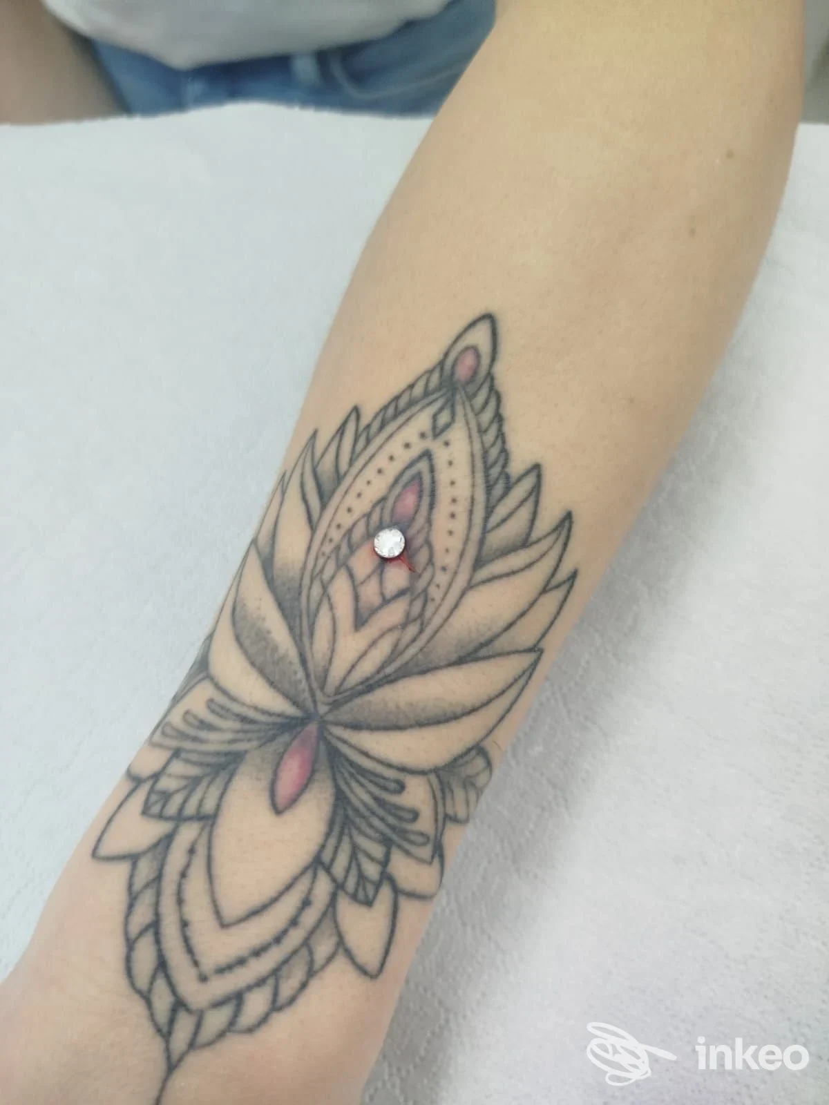 Tatuaggio ornamentale sull'avambraccio realizzato da Laboratorio Piercing, Taranto: linee nere con dettagli rosa sulla pelle.