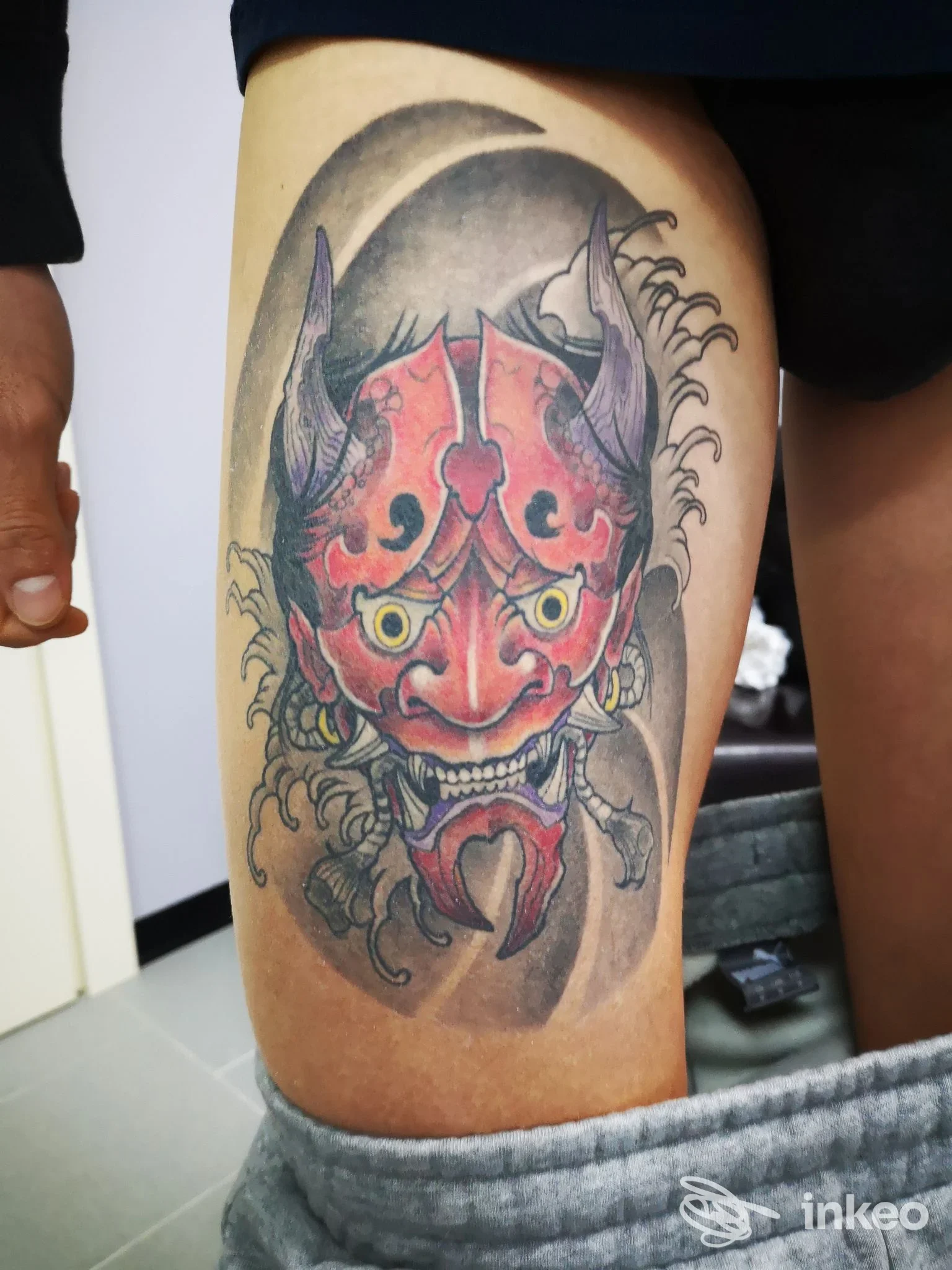 Tatuaggio su coscia con maschera demoniaca rossa, lavoro fotografato per Lotus Noir Tattoo Studio, Manduria.
