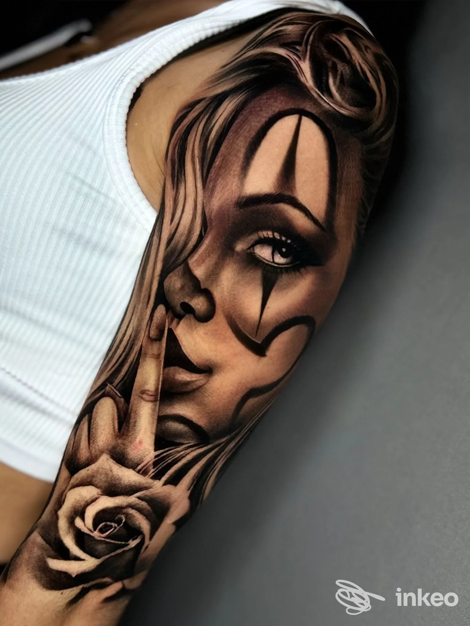 Grande tatuaggio realistico in bianco e nero di un volto clown e una rosa sul braccio, Luka Tattoo indelebile Ink, Mola di Bari.