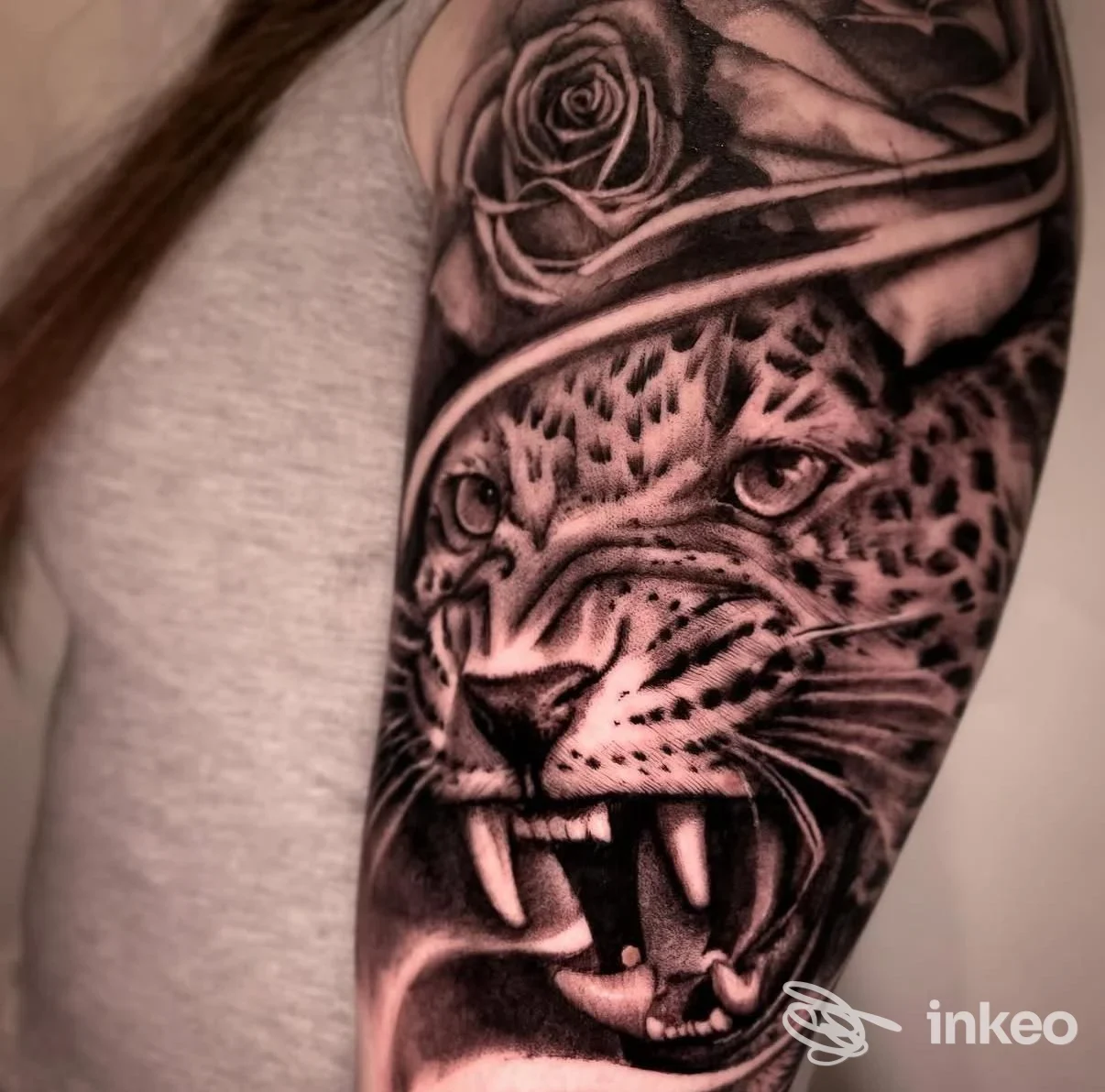 Tatuaggio realistico black & grey di un leopardo ruggente con rose su braccio superiore, foto dallo studio Grass Bad Tattoo a Bari.