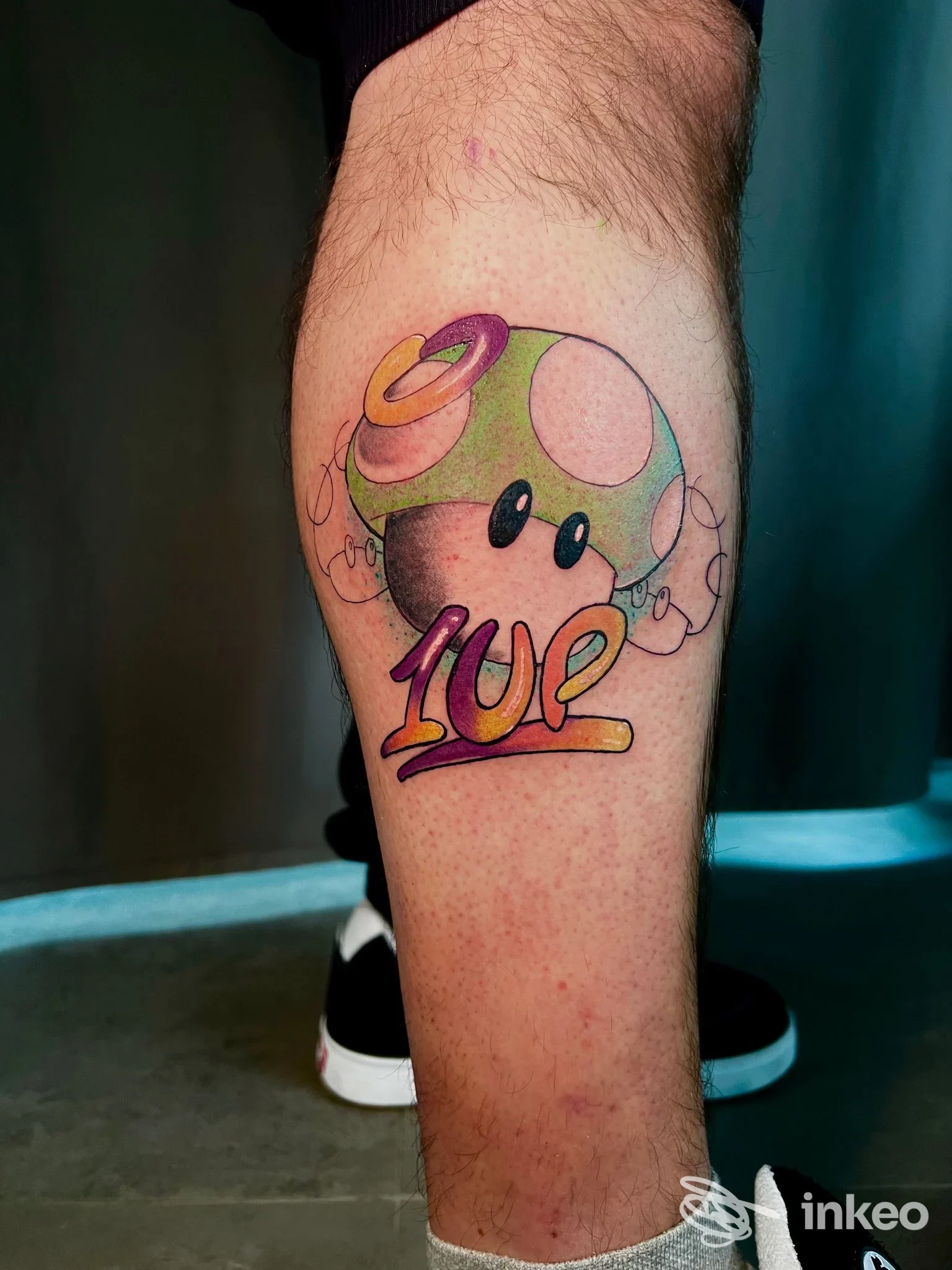 Tatuaggio colorato a tema '1UP' su polpaccio, realizzato da MAAD Tattoo Shop a Matino.