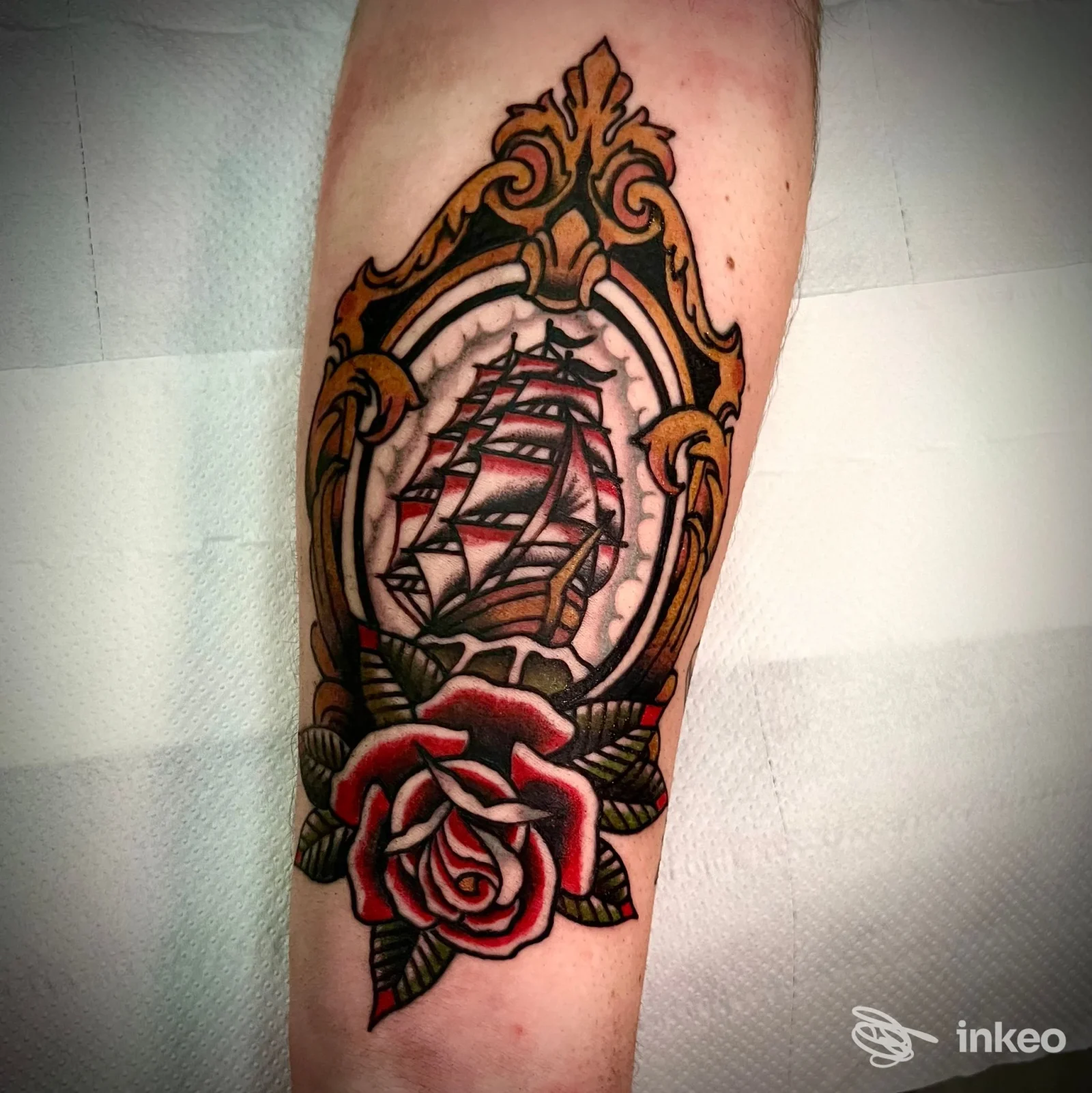 Tatuaggio tradizionale su avambraccio con nave in cornice ornamentale e rosa rossa, foto di Mama Forgive Me Tattoo Ostuni, Ostuni.