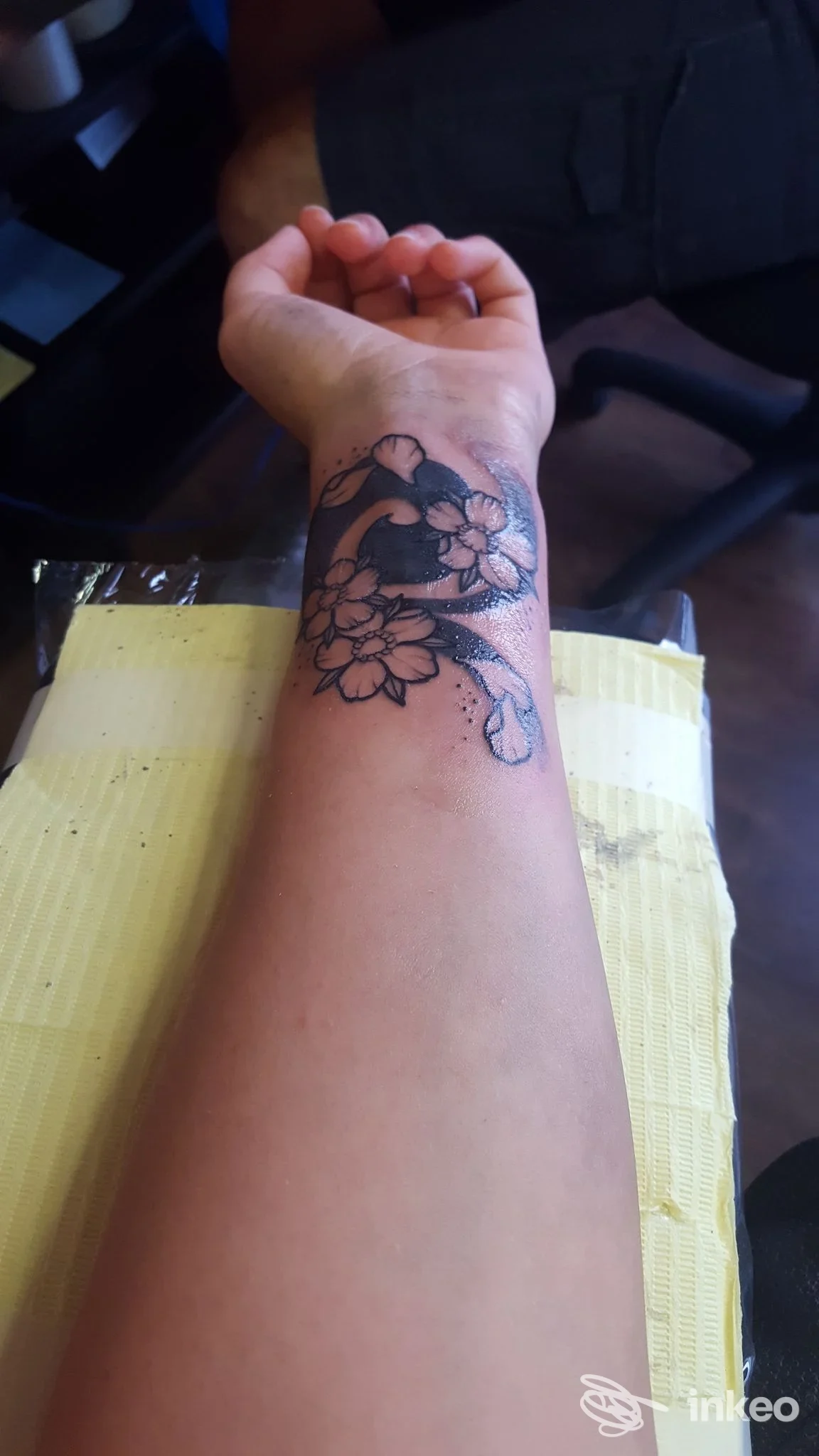 Avambraccio con tatuaggio floreale nero su pelle chiara, visibile in studio, senza volto.Studio L'Orientale Tattoo, Curno, Italia.